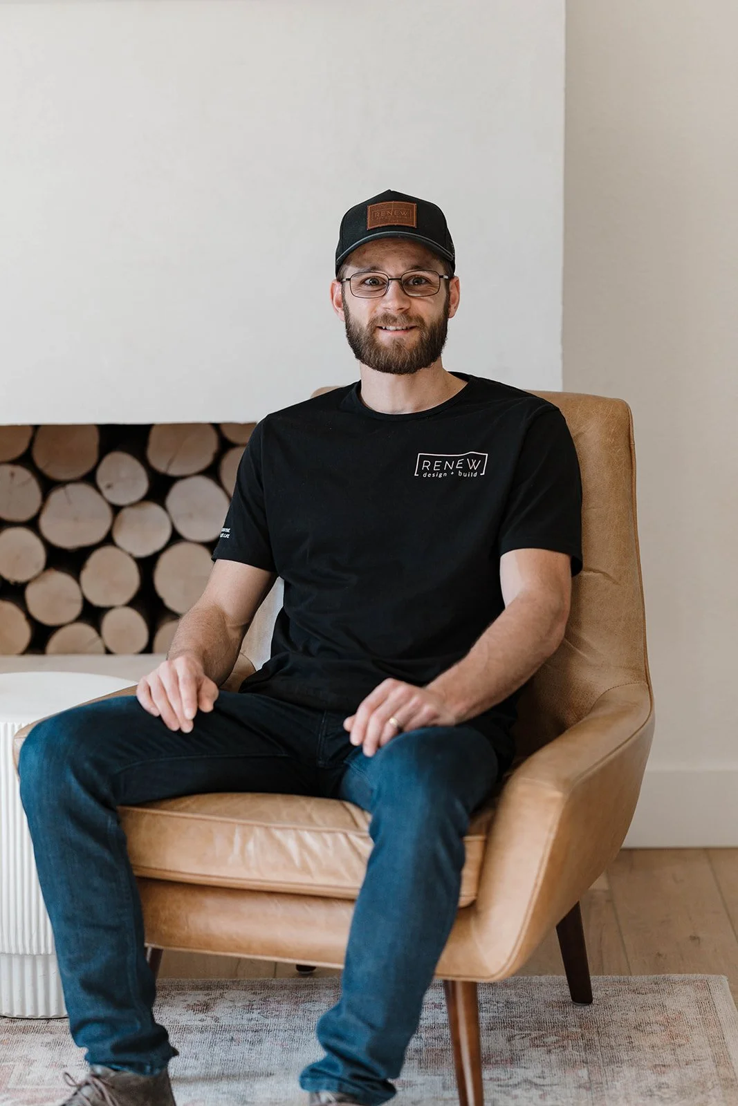 CEO of Renew Design + Build, Josh Kulla, sitting on a tan armchair in a cozy room.