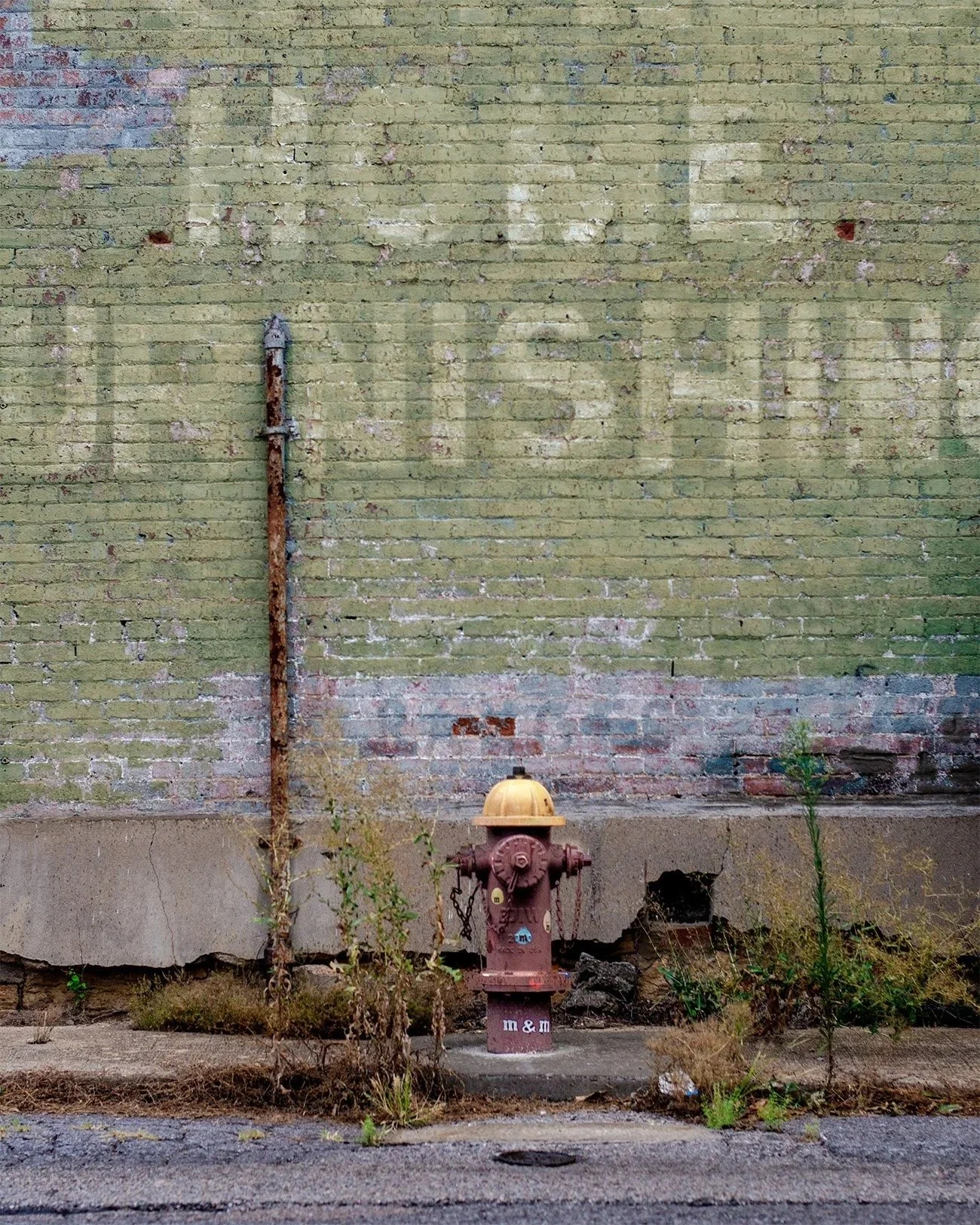 A brick exterior wall the the ghost sign of a furniture store.