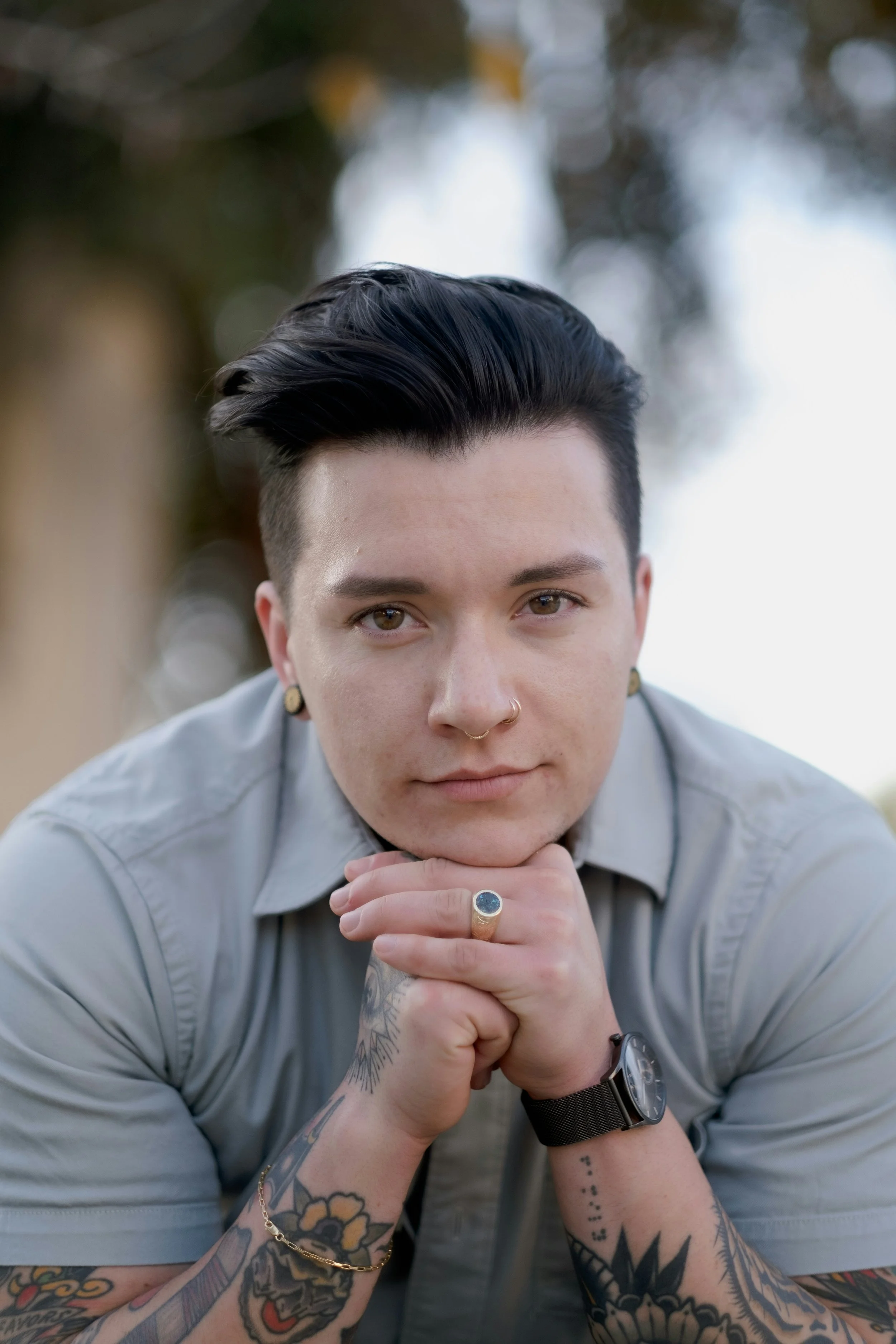 A masculine person with dark hair looks into the camera