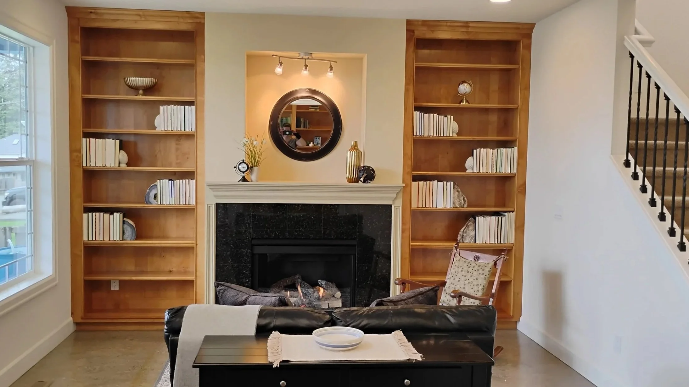 Living room with fireplace, two bookshelves, and a leather couch