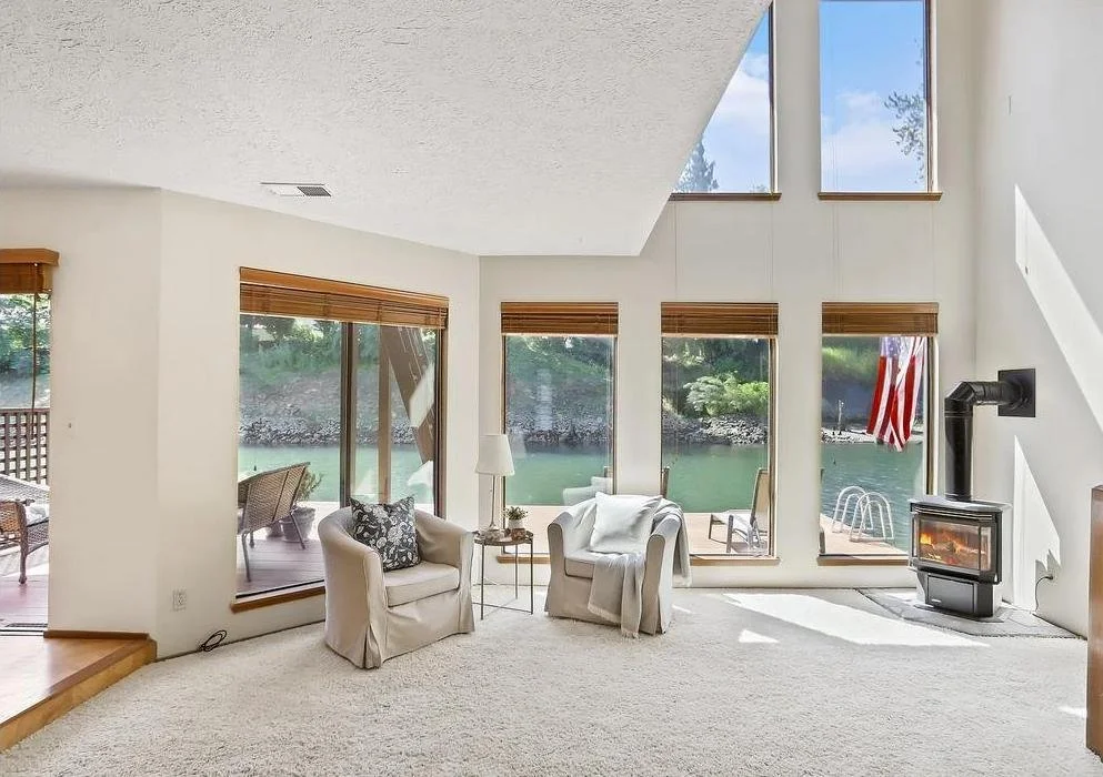 Carpeted living room with large windows looking out to water