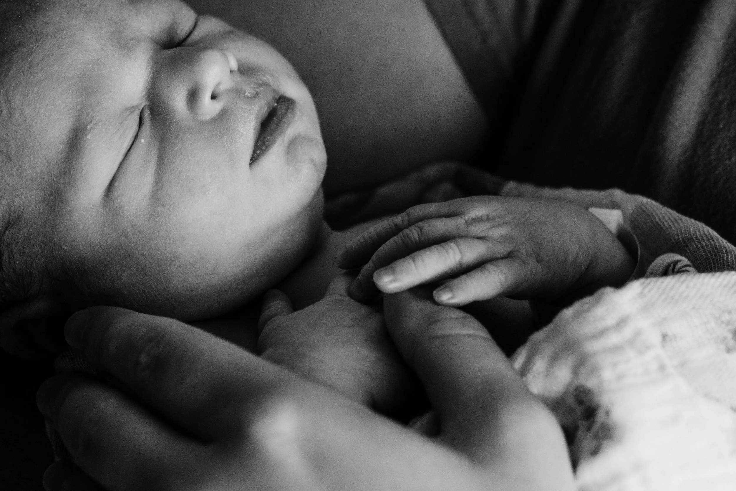 A sleeping newborn baby being gently held by parents 