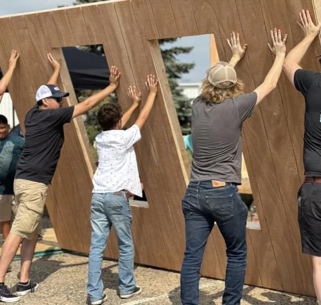 People working together to construct a large wooden structure outdoors.