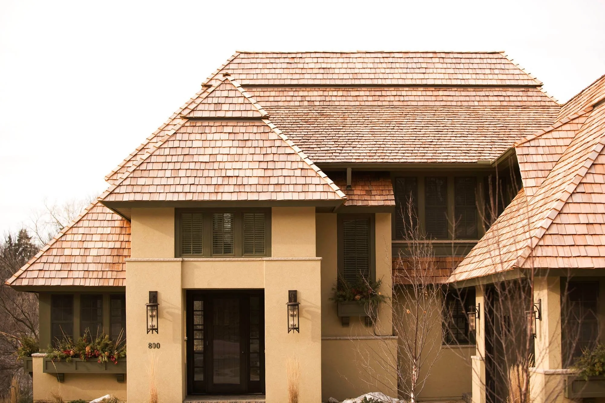 Front view of a beige house with a brown tiled roof, black front door, and decorative outdoor lanterns.