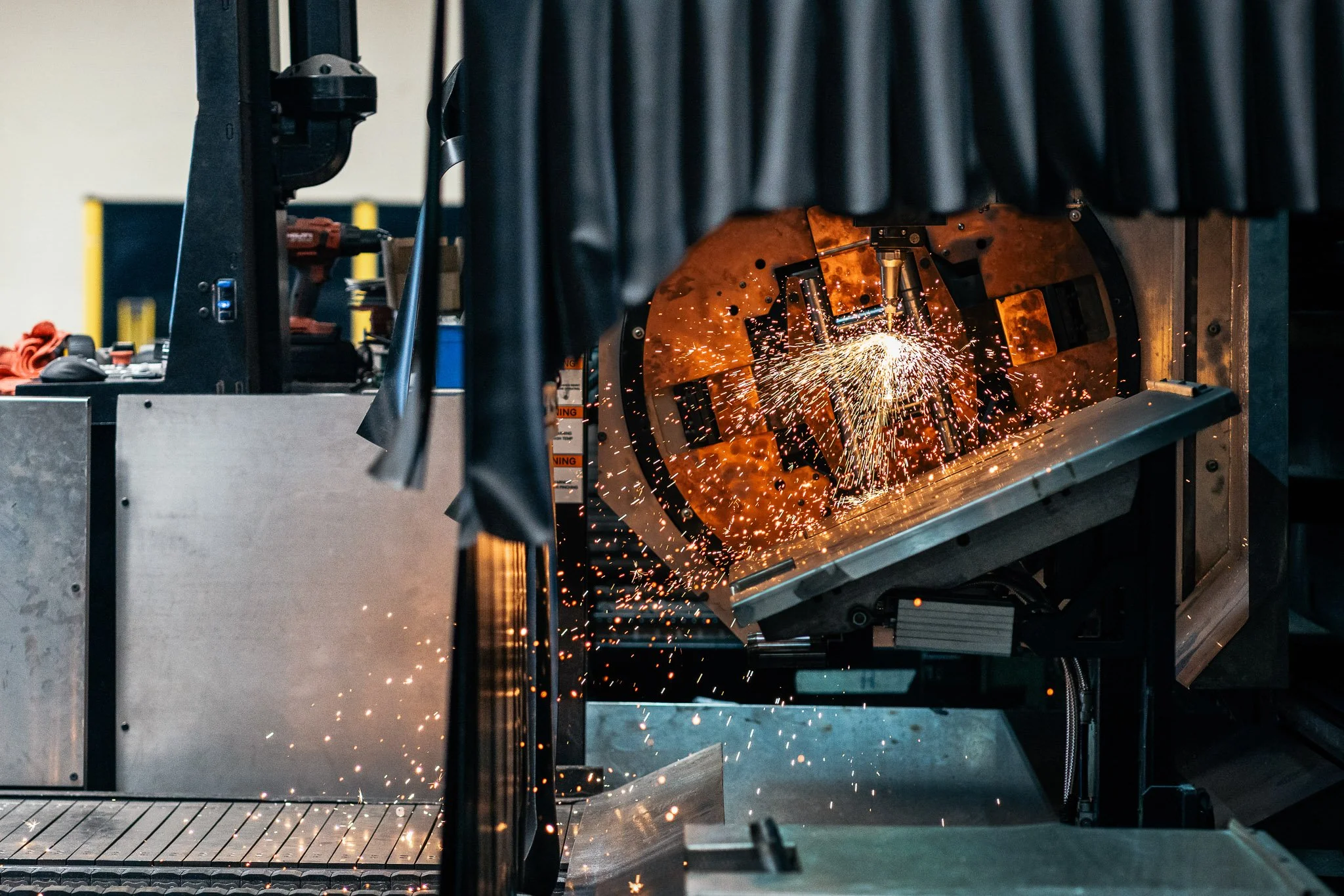A machine welding metal with sparks flying during the welding process.