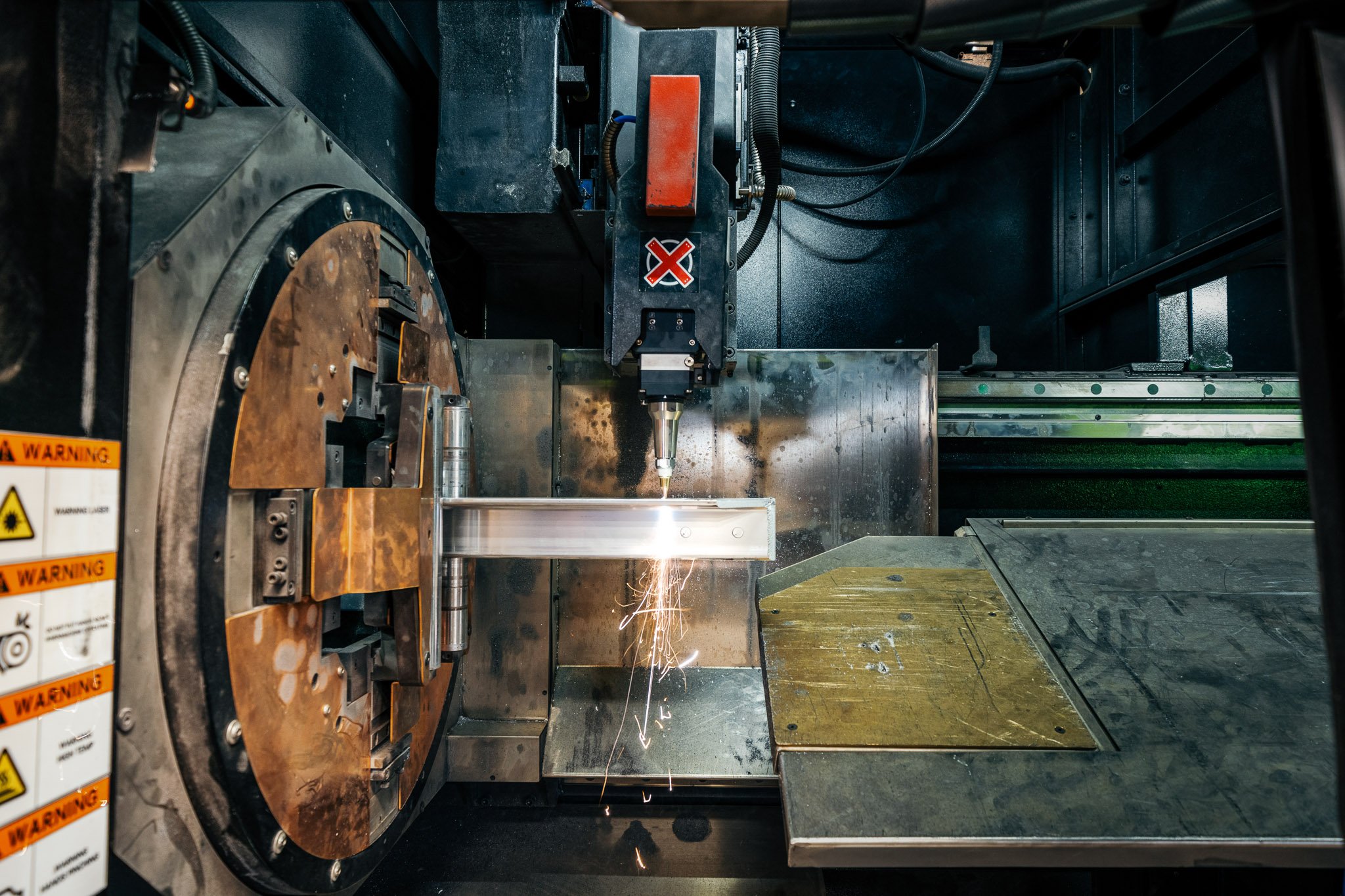 A CNC machine or industrial manufacturing equipment with sparks flying as it cuts or welds metal parts.