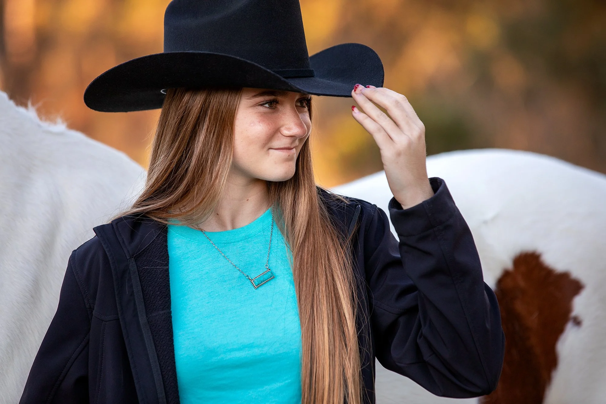 teal cowgirl, tipping black hat, with paint gelding