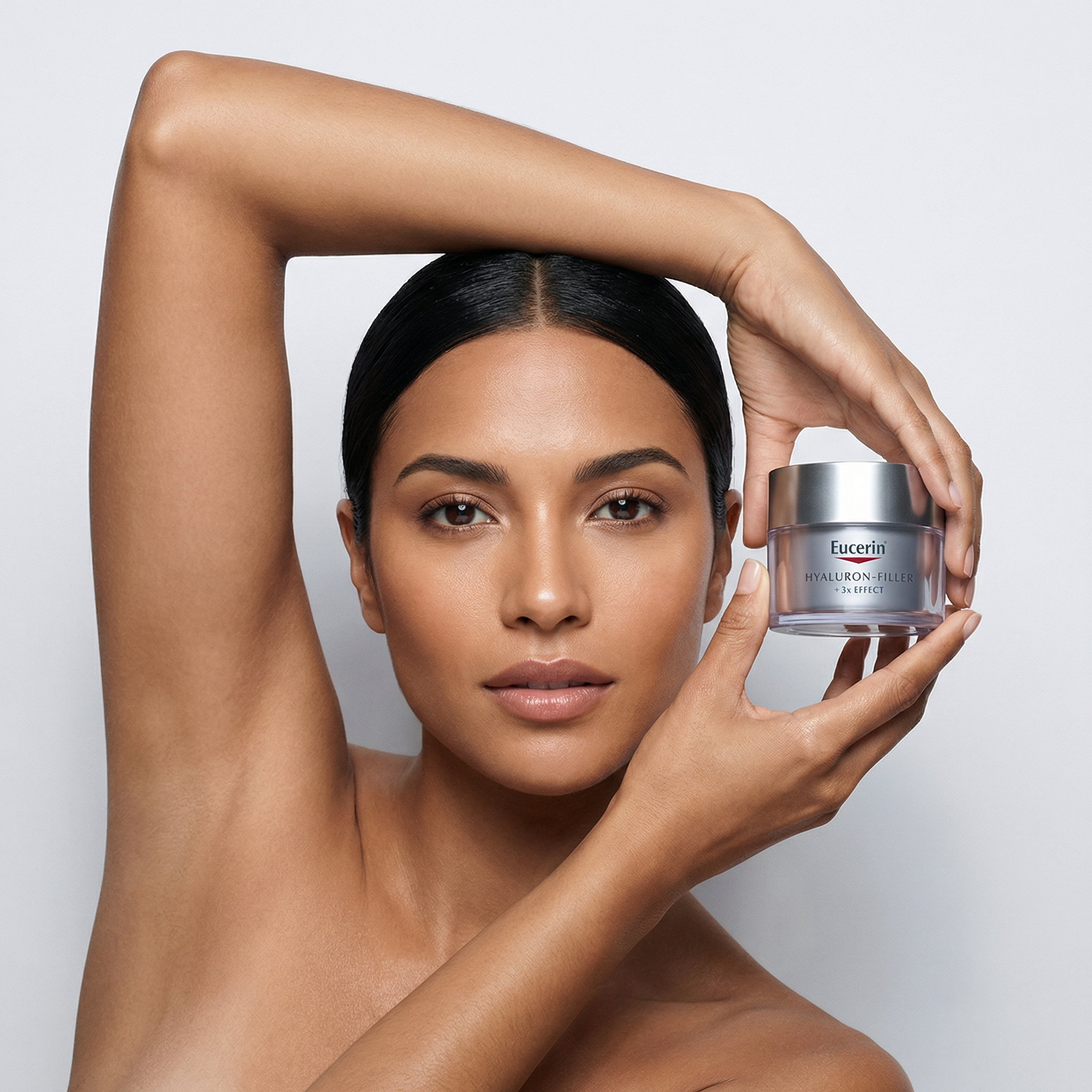 Mujer con piel radiante sosteniendo un frasco de crema hidratante Eucerin con fondo gris claro.