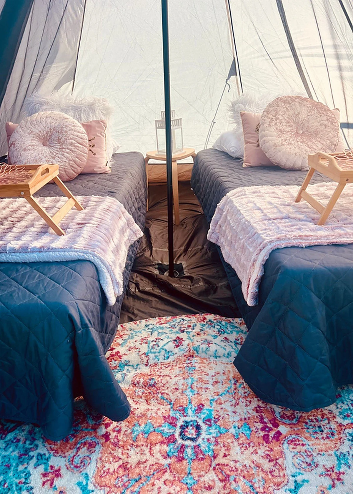Camp Ready: inside a pitched bell tent with two made-up twin beds, side tables and a patterned rug.