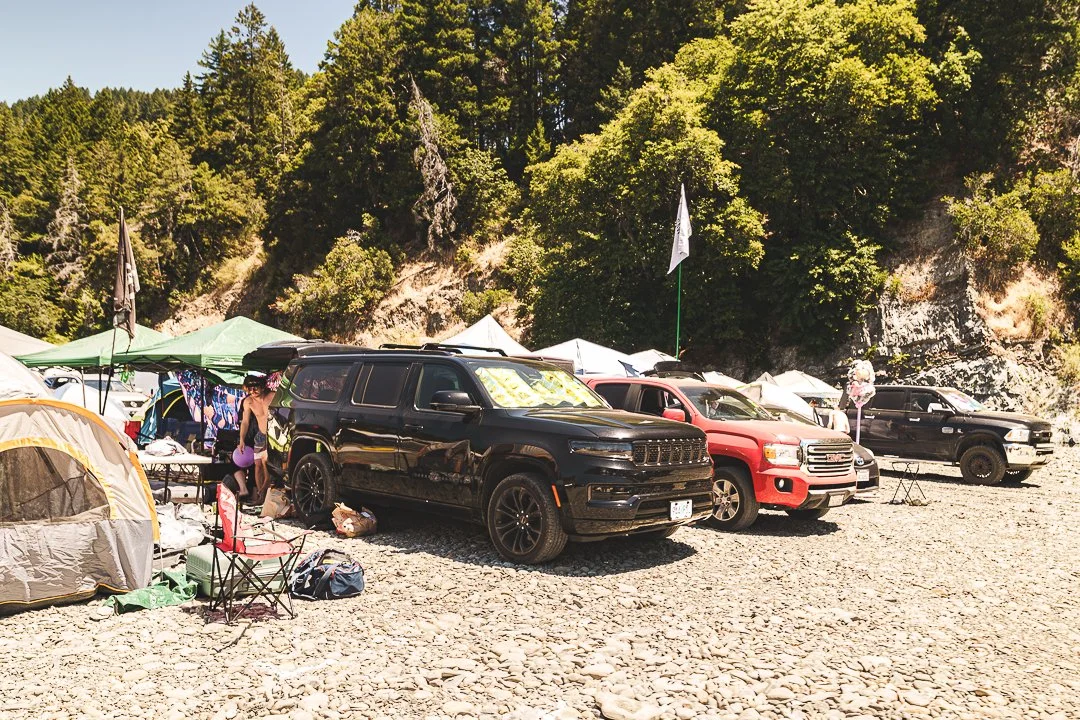 4x4 Camping: trucks and SUVs parked beside tents below a wooded hillside at Northern Nights.