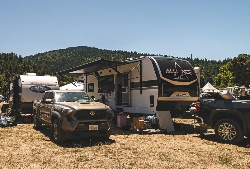 RV Camping: travel trailers and trucks parked on a dry field under a blue sky at Northern Nights.