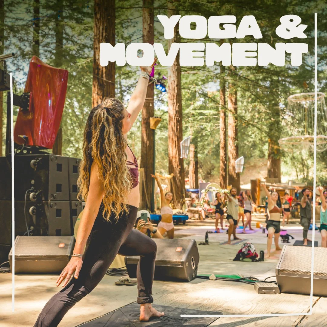 A woman leading a yoga class outdoors in a forested area, with other participants in the background practicing yoga poses.