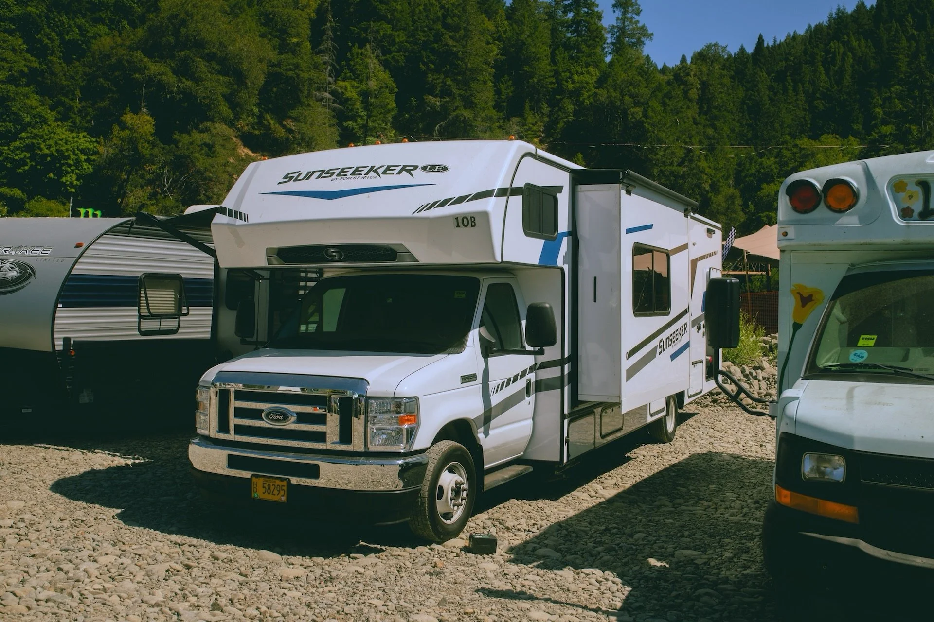 River RV Camping: a white motorhome parked among tall trees near the river at Northern Nights.