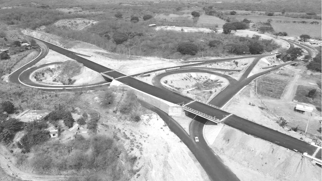 Imagen aérea de una construcción de una nueva intersección de carreteras con varias vueltas y rampas en una zona rural con árboles y campos