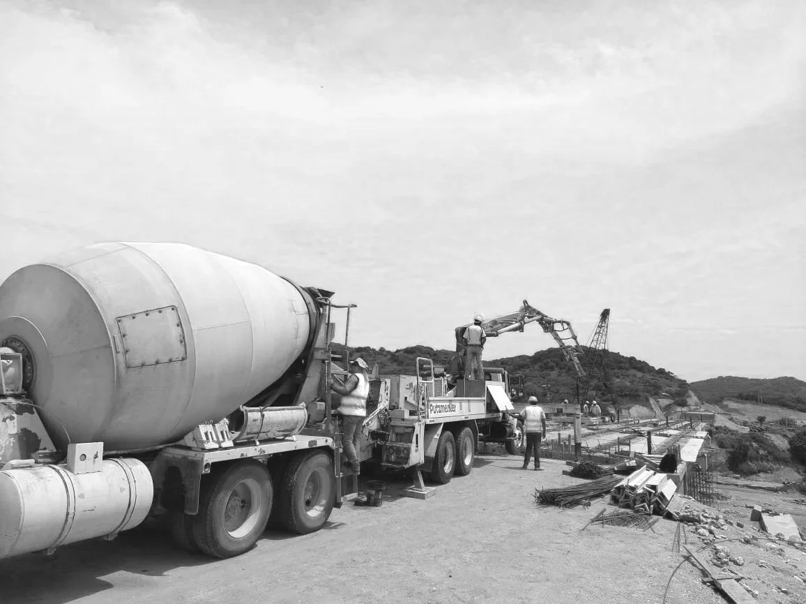 Construcción de un puente o estructura similar con maquinaria pesada y varios trabajadores en el sitio.