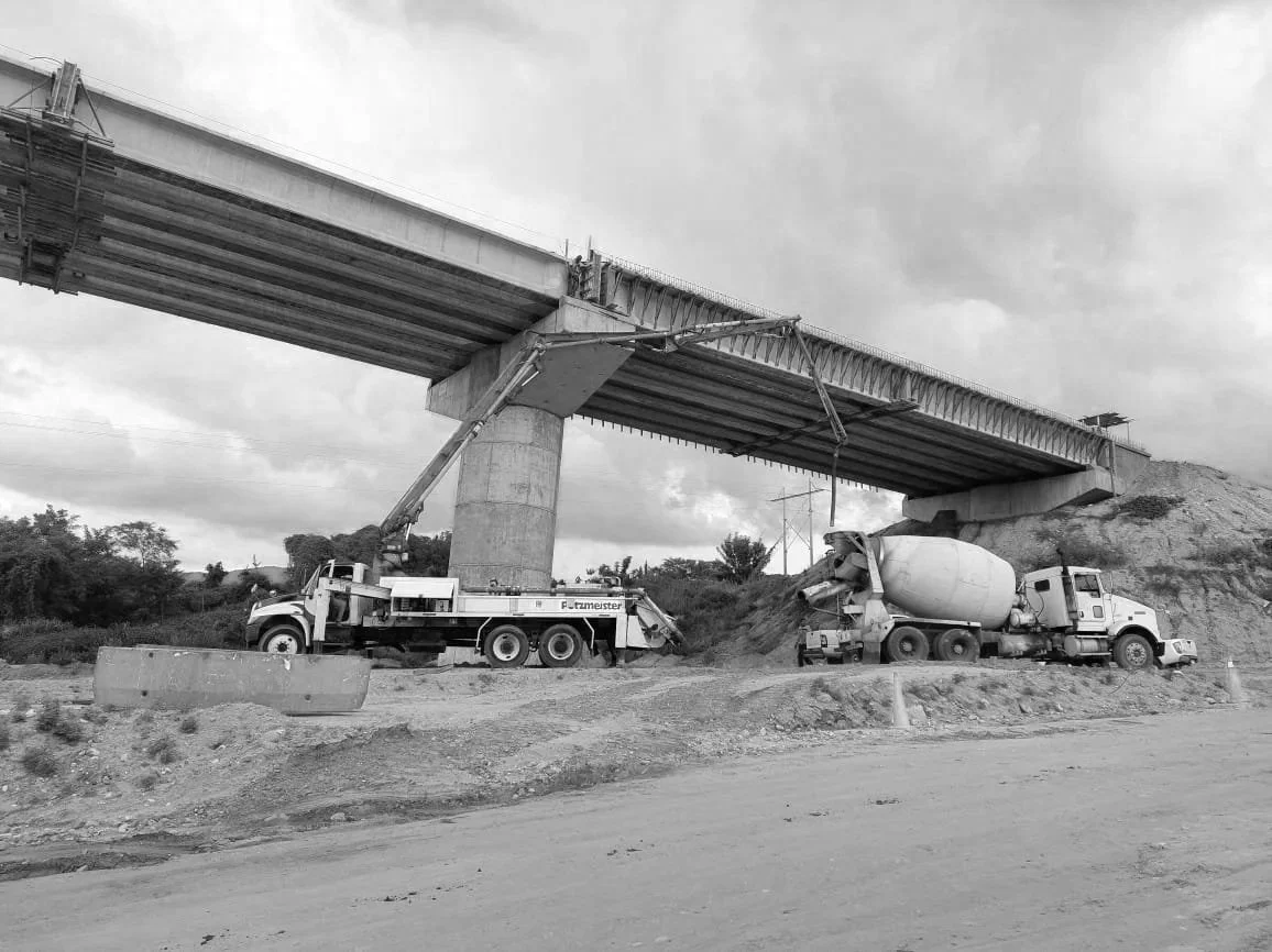 Construcción de un puente con dos vehículos mezcladores de cemento y maquinaria de construcción en el sitio.
