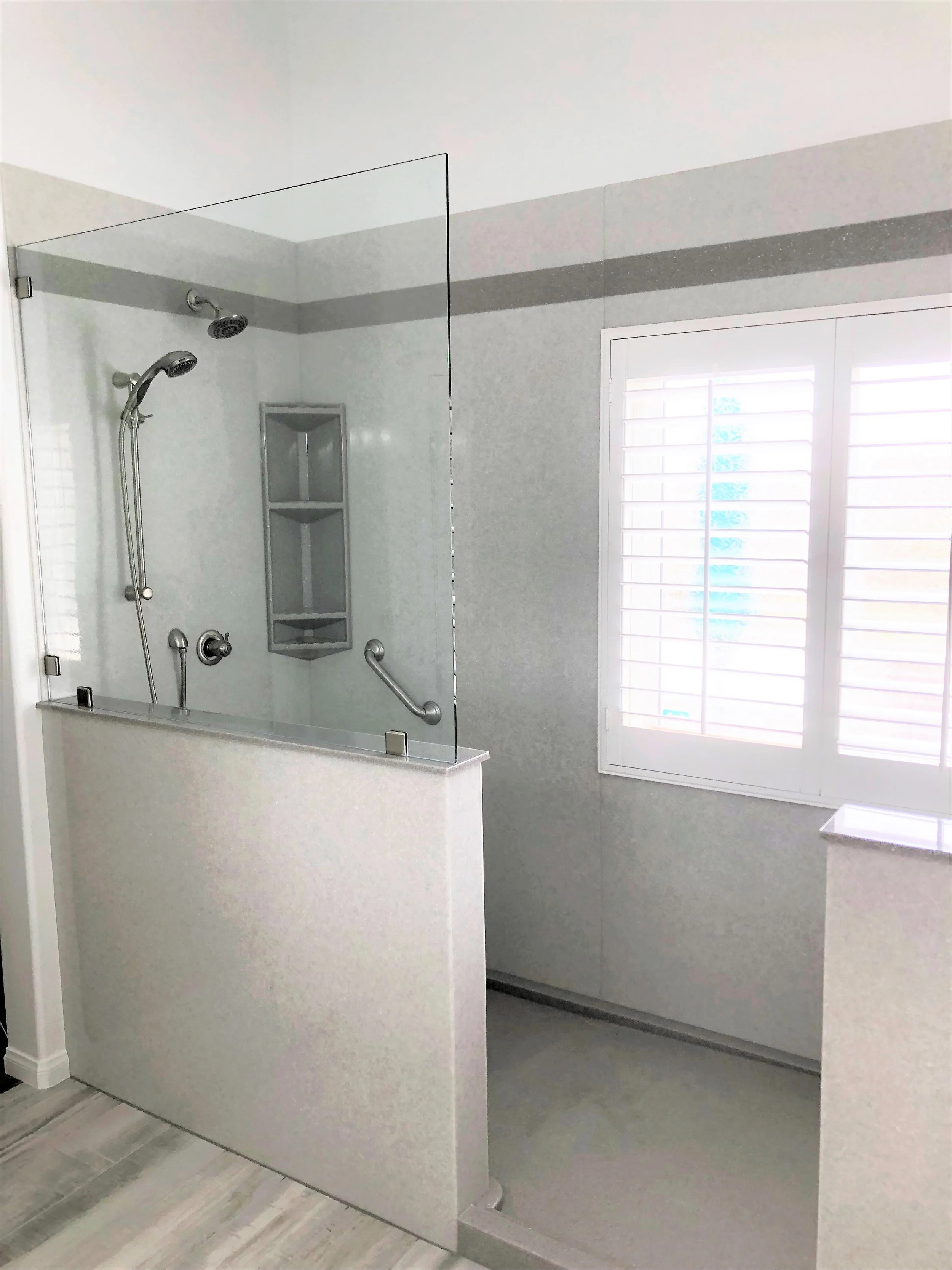 Walk-in shower installation with accessibility grab bars and glass partition