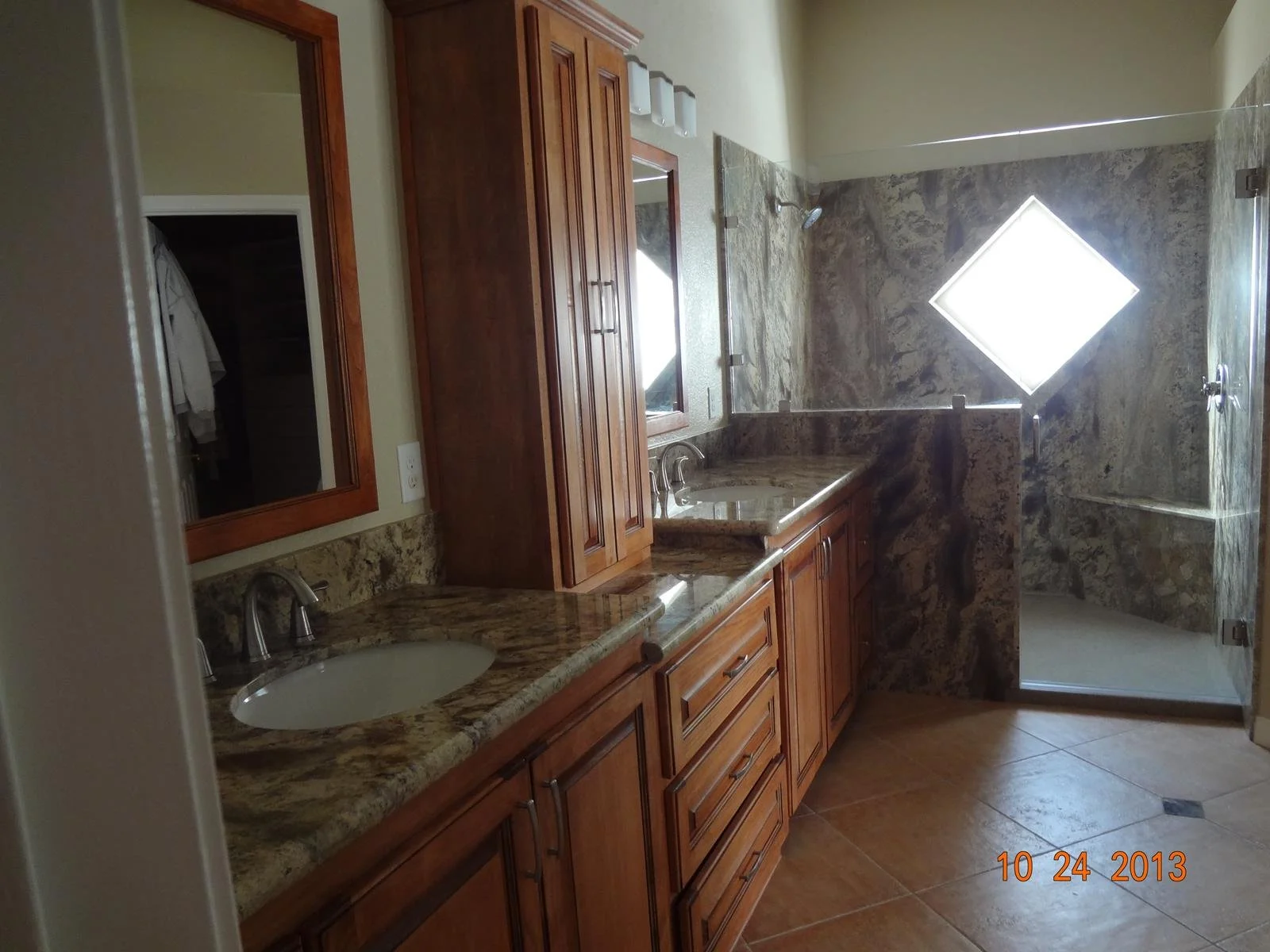 Double sink bathroom vanity with stone countertops and glass shower enclosure