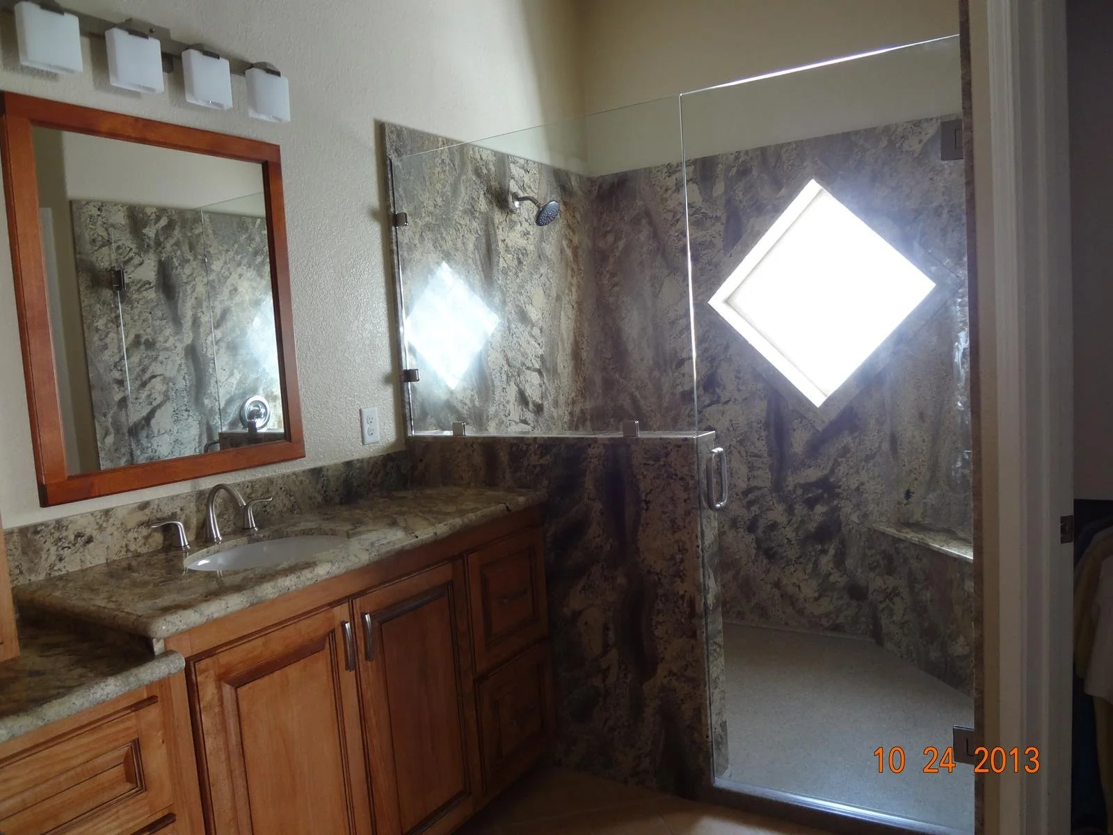Bathroom remodel featuring granite vanity countertops and custom walk-in shower