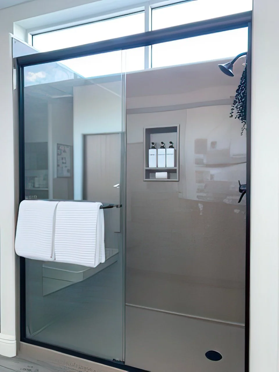Contemporary bathtub shower remodel with matte black fixtures, built-in wall niche, and minimalist white tile surround.