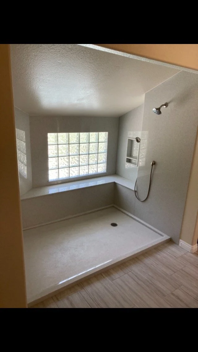 Large open walk-in shower with bench seating, glass block window, and low-threshold entry for accessibility bathroom upgrade