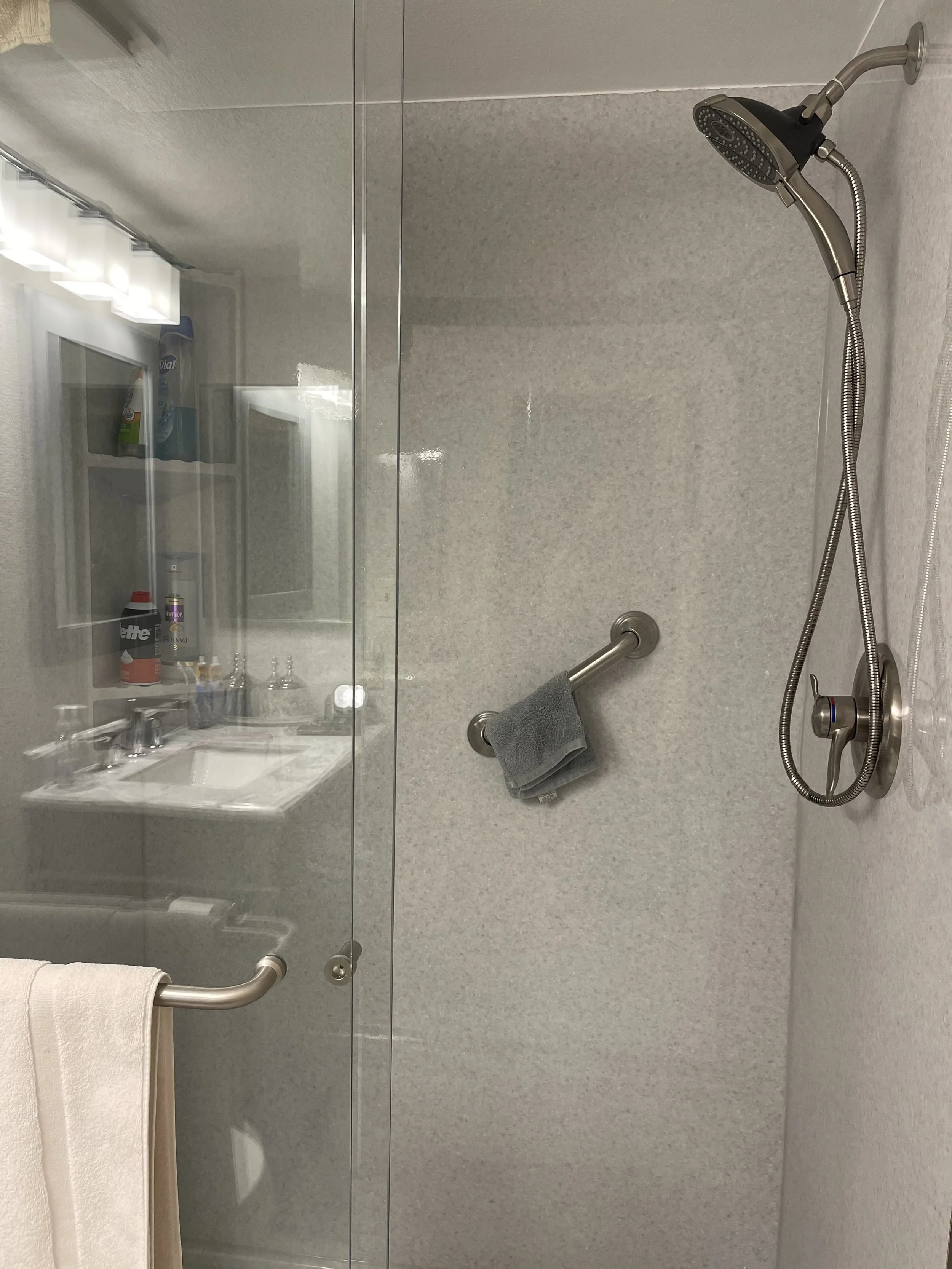 Accessible walk-in shower installation with safety grab bars, handheld showerhead, corner seat, and low-curb shower base