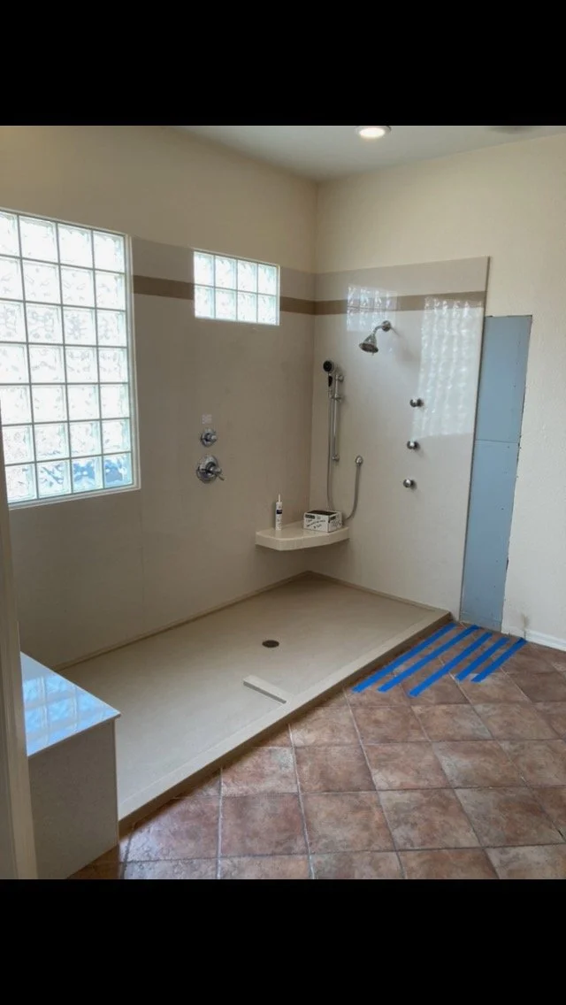 Accessible roll-in shower remodel with corner bench, grab bars, handheld shower wand, and slip-resistant flooring