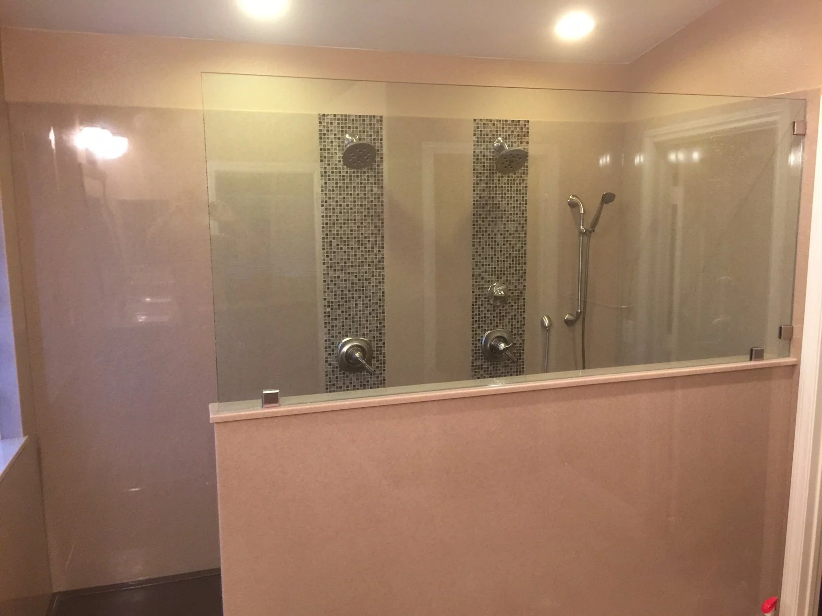 Custom glass shower enclosure with towel bar, built-in shelving niche, and textured stone shower walls.