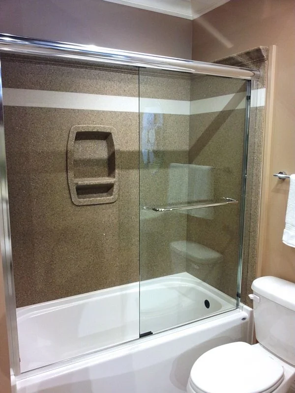 Tub to shower conversion with glass enclosure, built-in bench, and decorative tile accent border.
