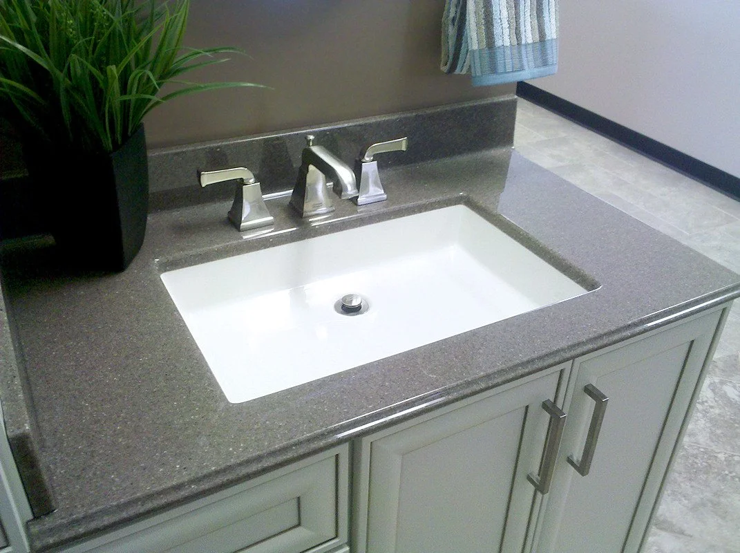 Bathroom vanity remodel featuring undermount sink, quartz countertop, brushed nickel faucet, and gray shaker cabinets.