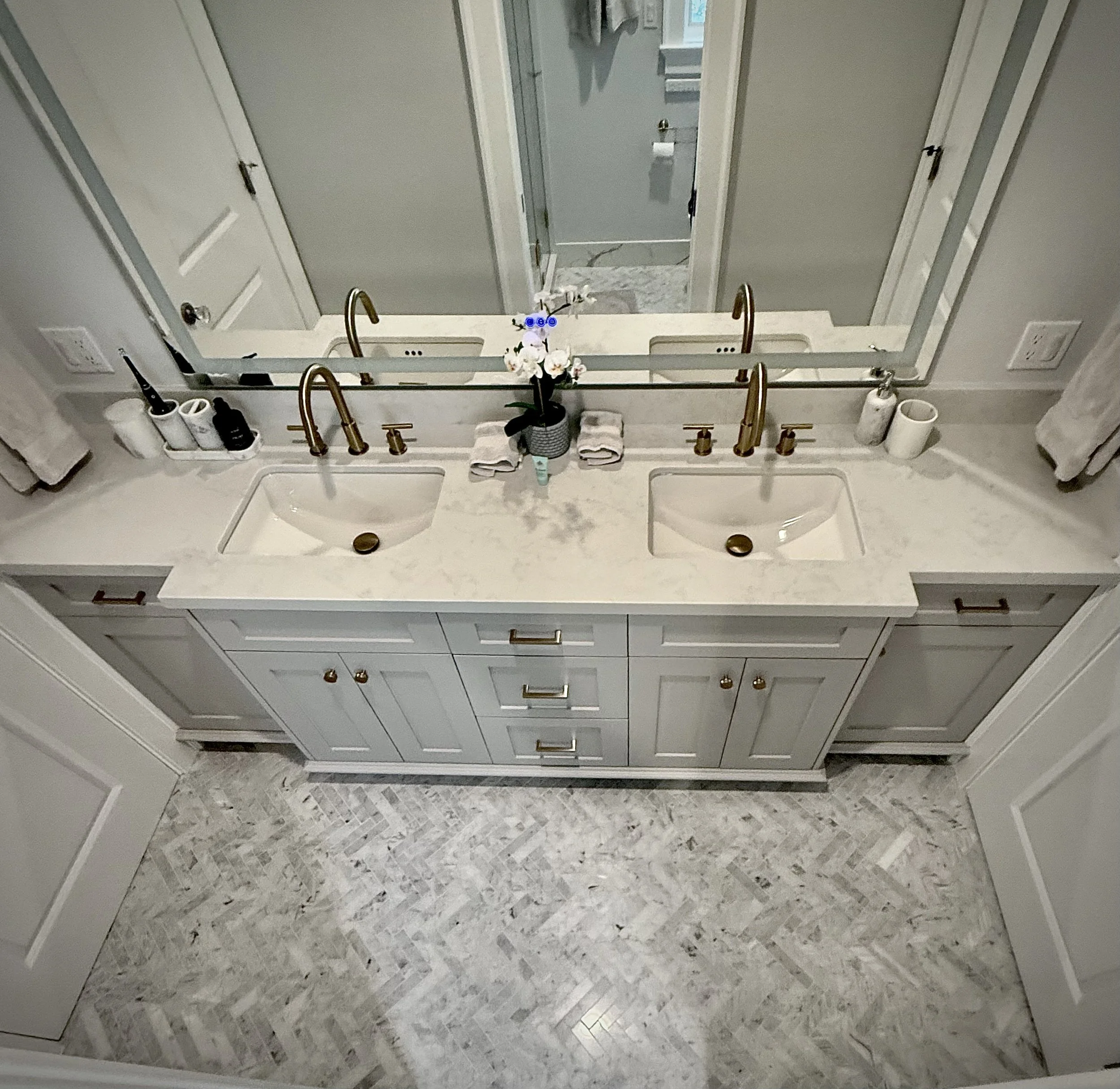 Custom double vanity with mosaic tile flooring and premium fixtures