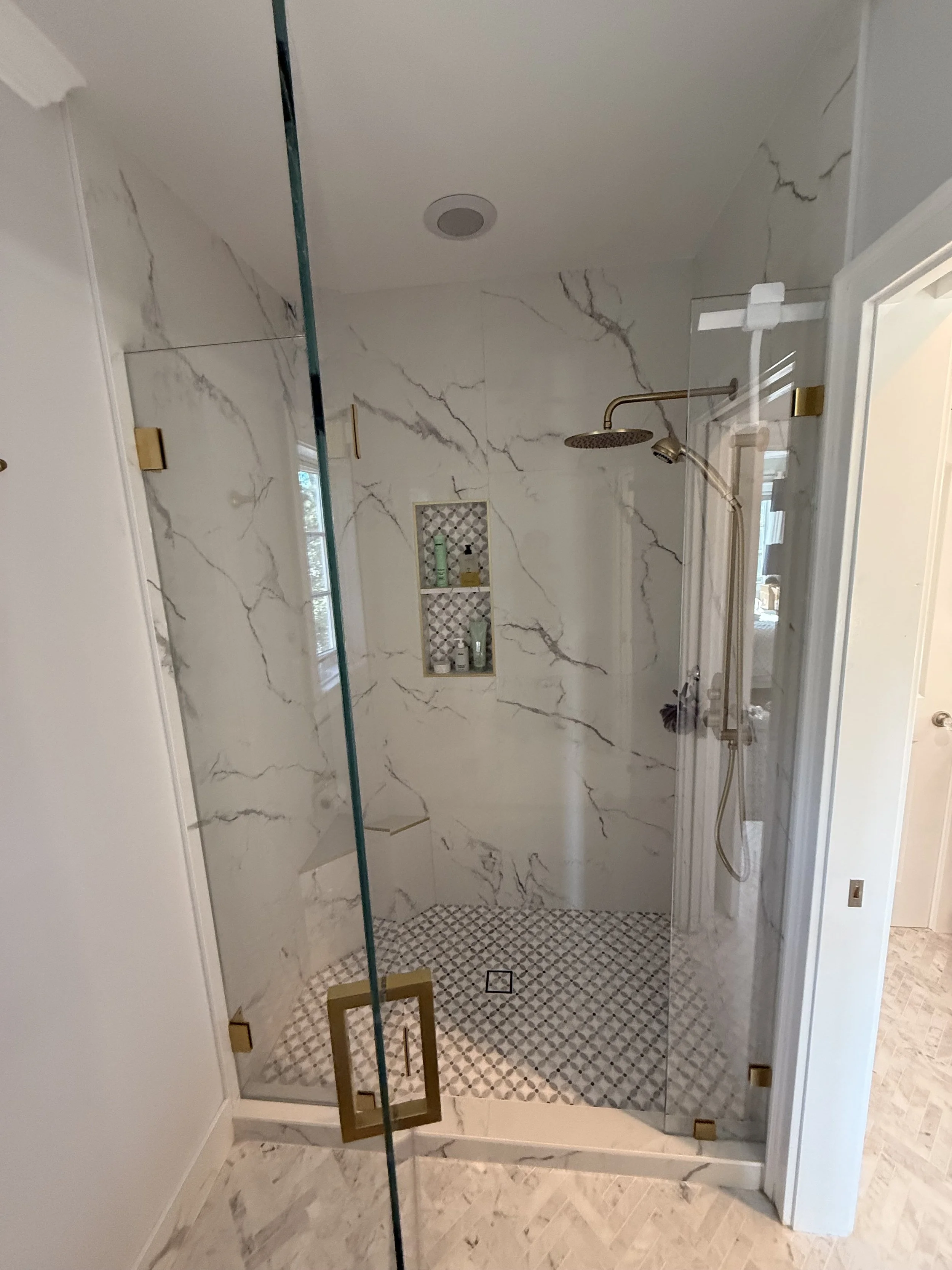 Modern walk-in shower with marble tile and brushed gold fixtures