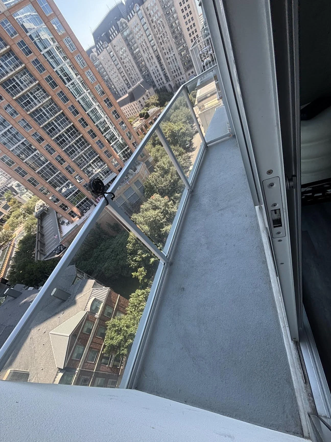 View from a balcony showing adjacent high-rise buildings and a city street below.