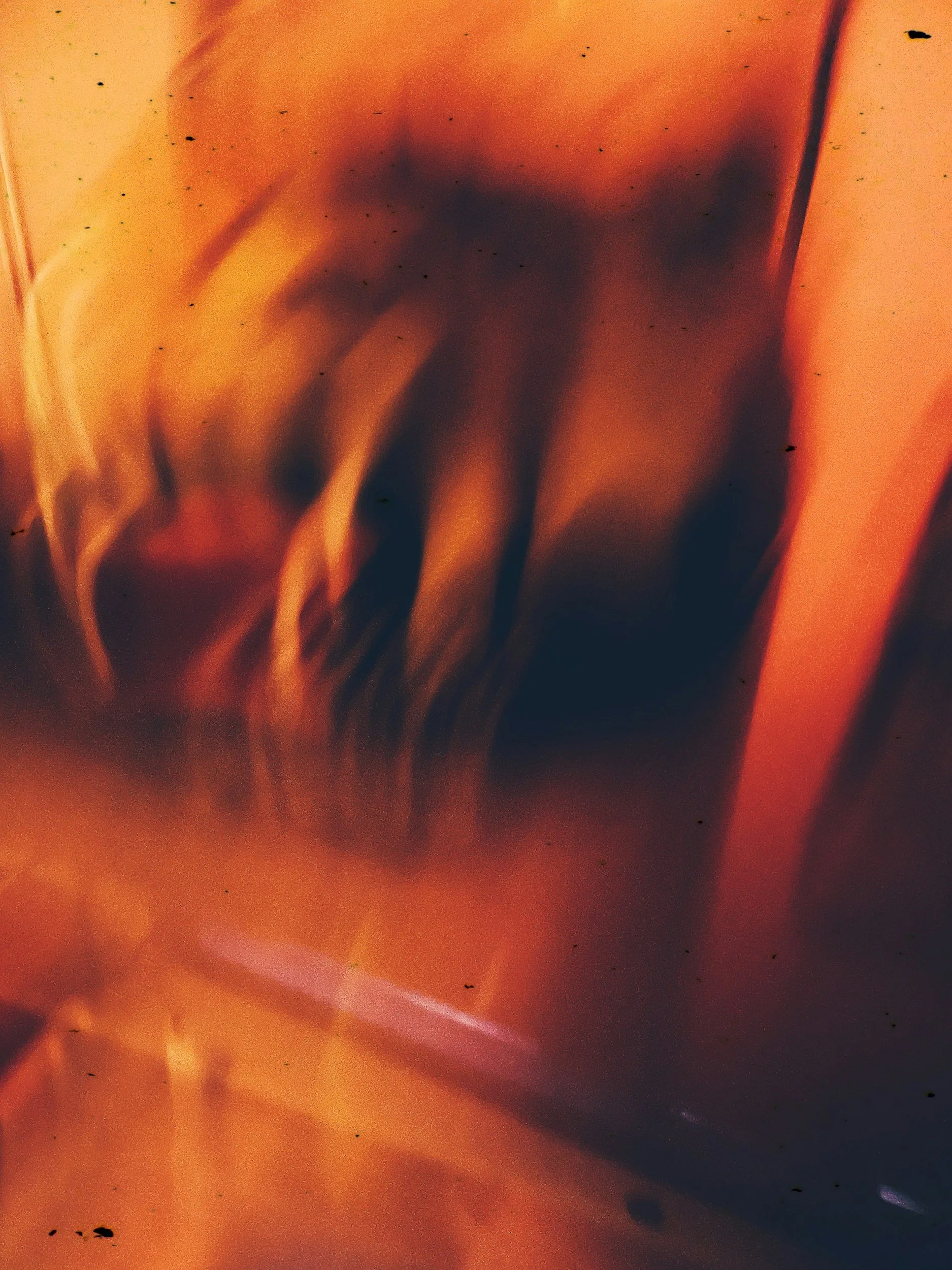 An abstract close-up with swirling orange, dark, and reddish tones, creating a blurred, fluid appearance.