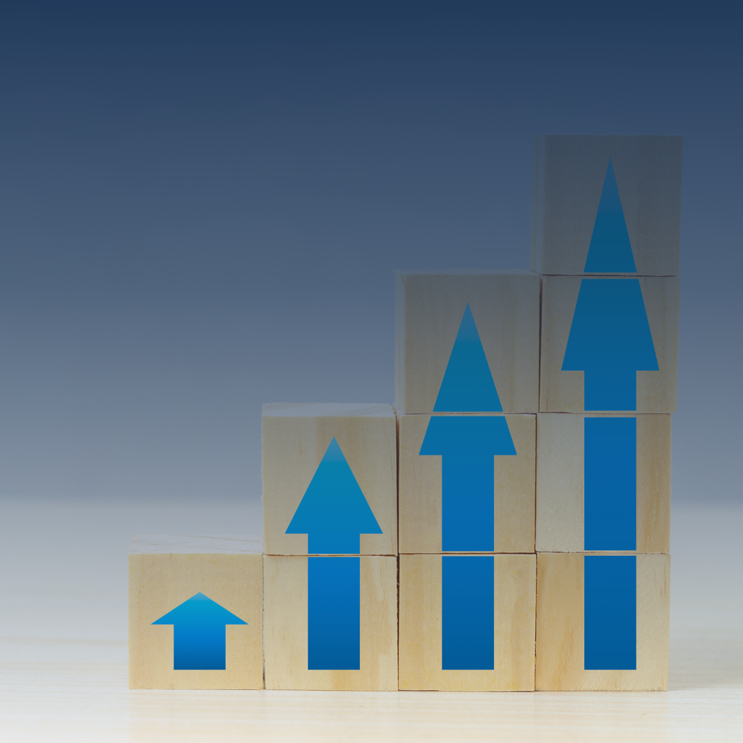 Stacked wooden blocks with blue upward arrows, symbolizing growth or progress.