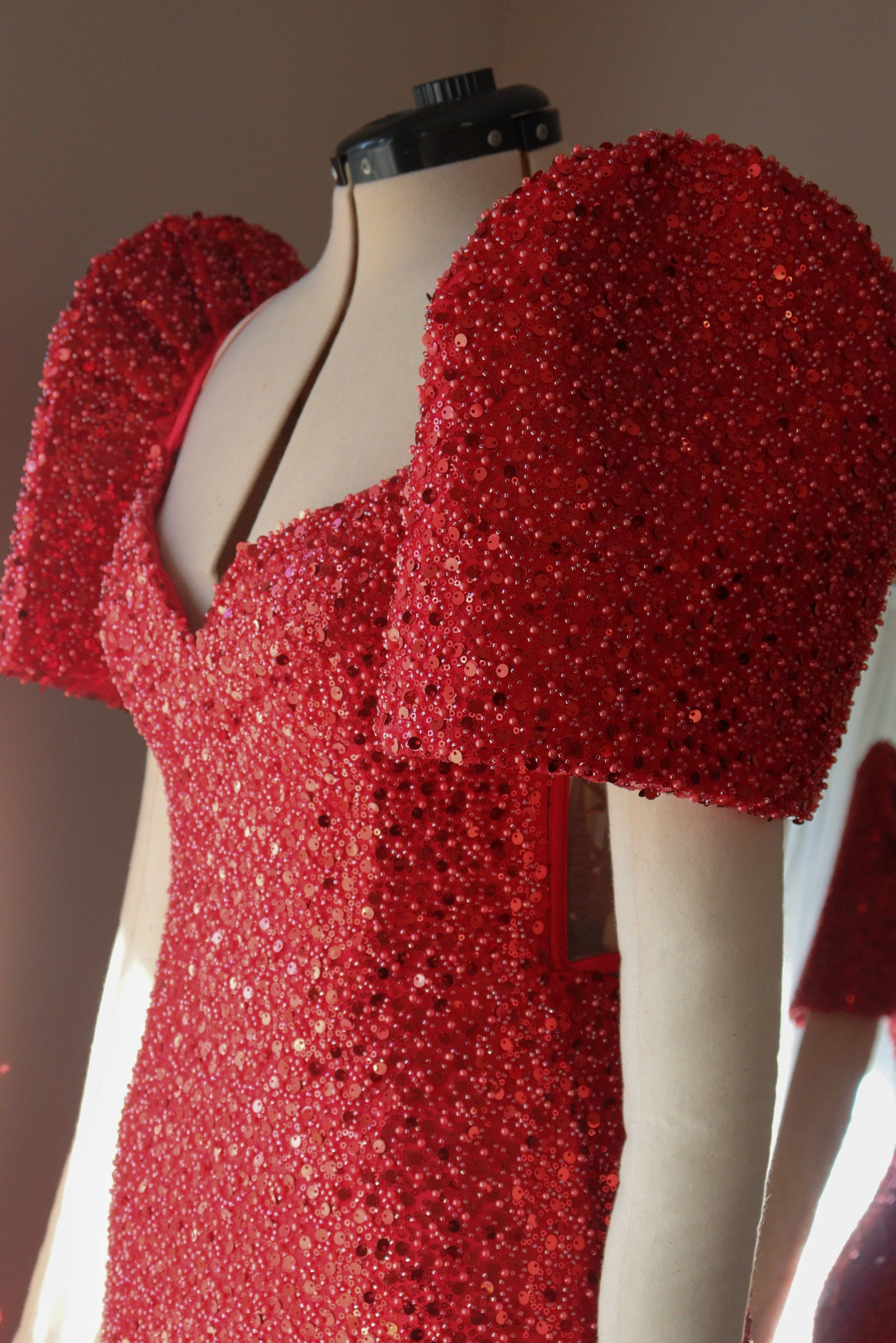 A mannequin dressed in a red, sequined gown with puffed sleeves.