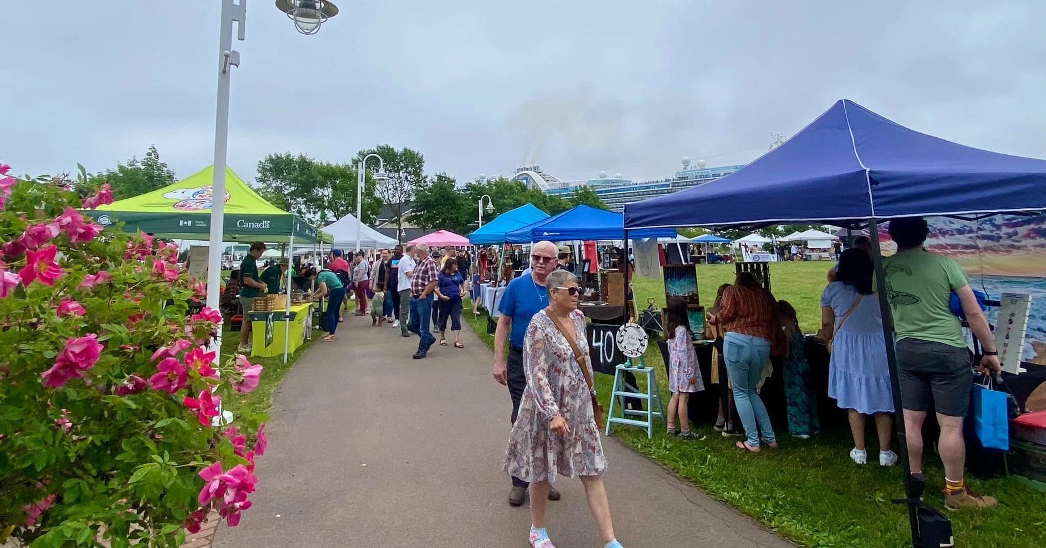 Outdoor Downtown Charlottetown Market with vendor tents and shoppers walking along the market located at the Confederation Landing Park.