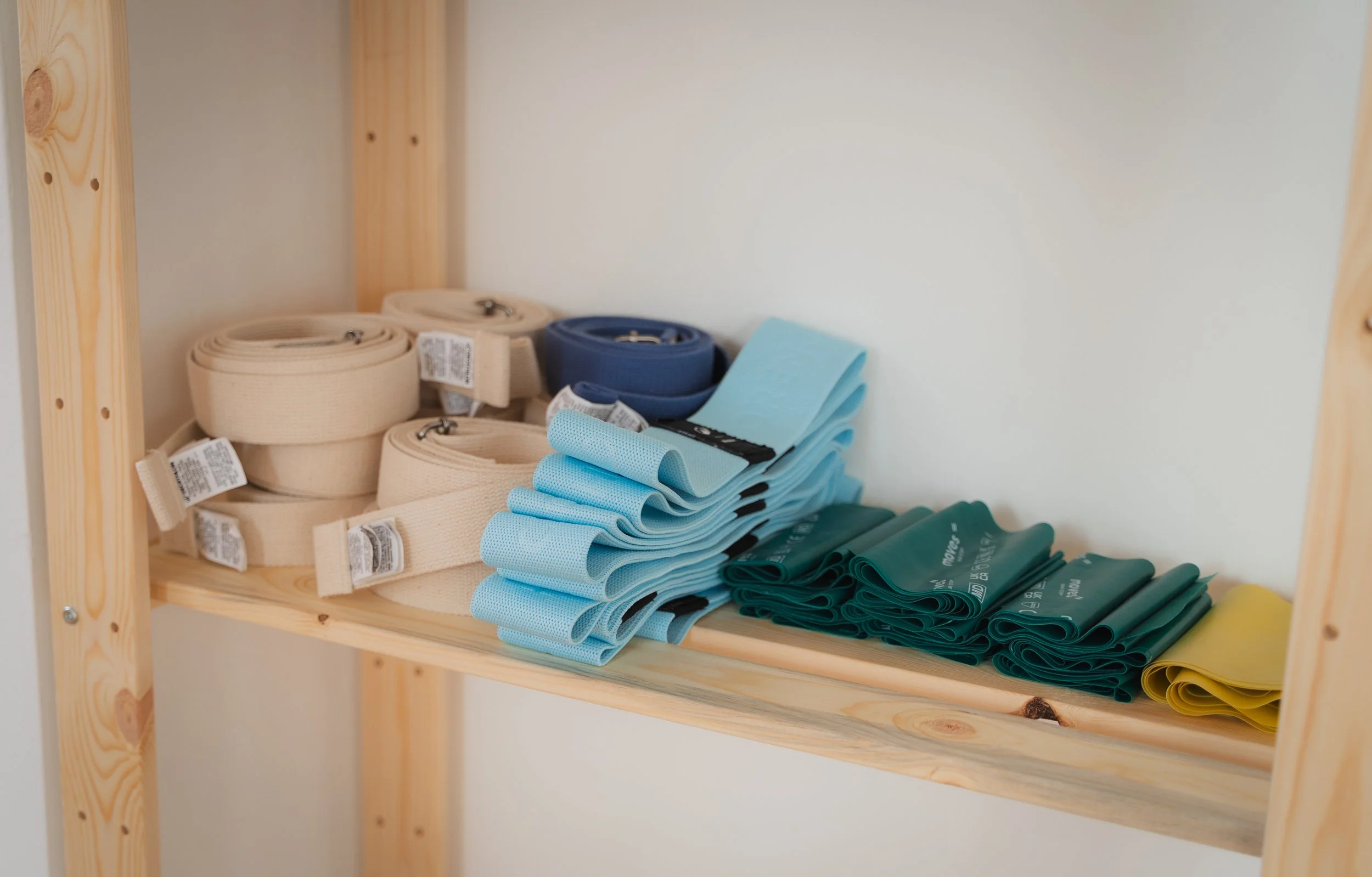 Stainless steel shelves holding rolled and folded elastic bands in various colors, on a wooden shelf.