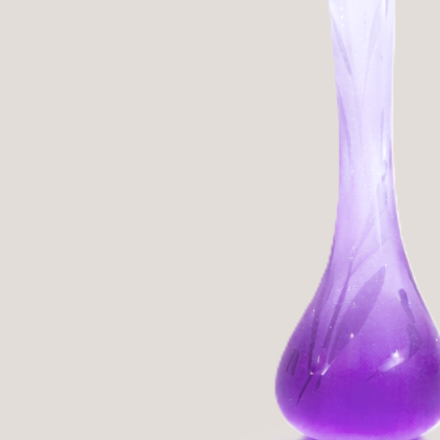 A purple and clear glass vase with a slender neck, positioned against a plain background.