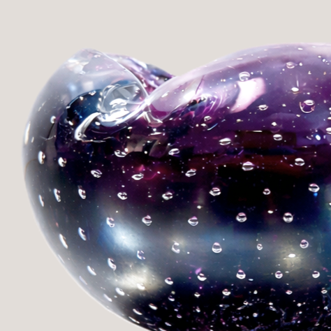 Close-up of a glass heart sculpture with water droplets, purple and blue hues, and a clear background.