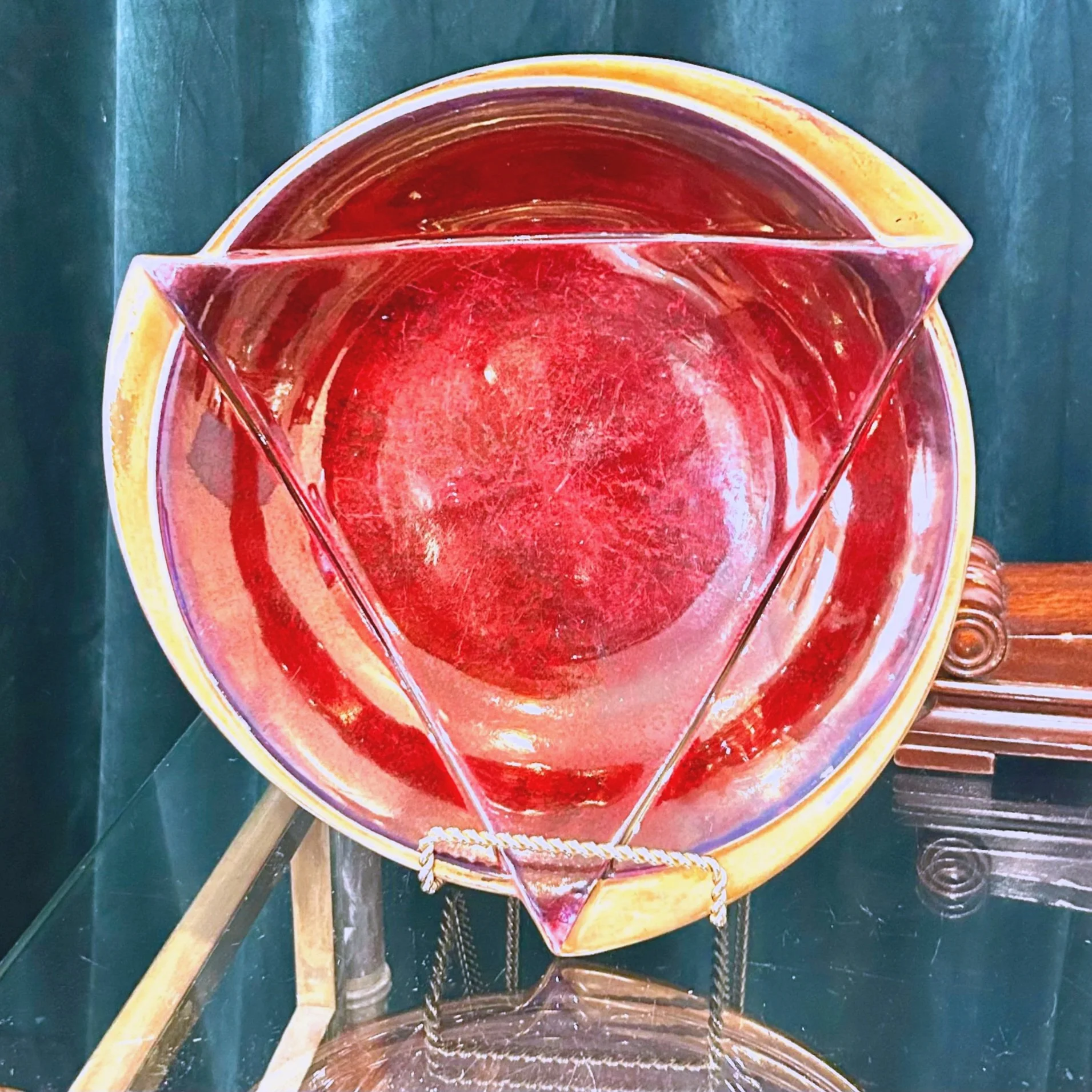 Colorful painting depicting a red, yellow, orange, and brown abstract scene with elements resembling a bowl, stick, and a dark background.