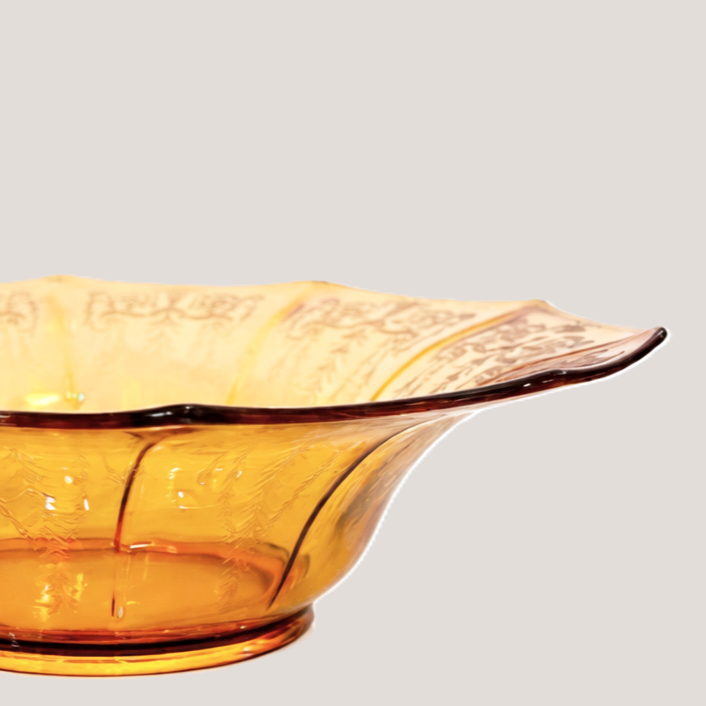 Amber-colored glass bowl with a decorative, wavy edge on a plain background.