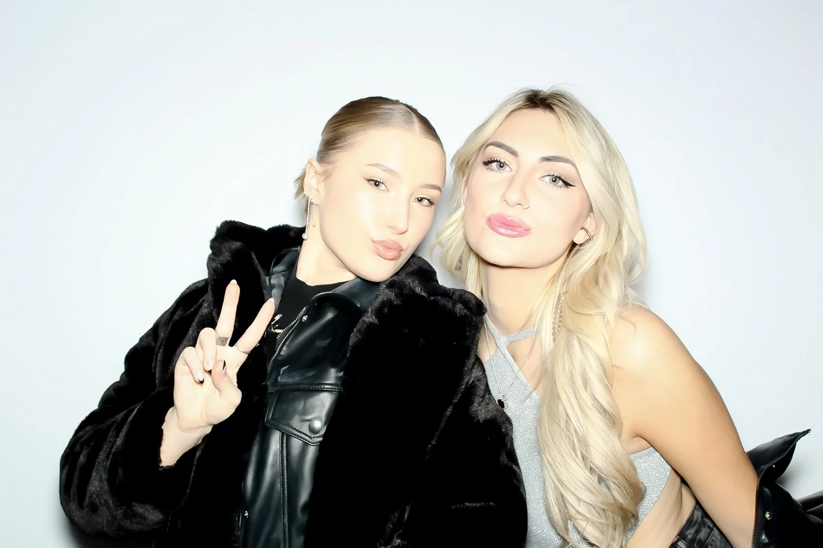 Two women taking a selfie together, one with dark hair and the other with blonde hair, both making duck face expressions.