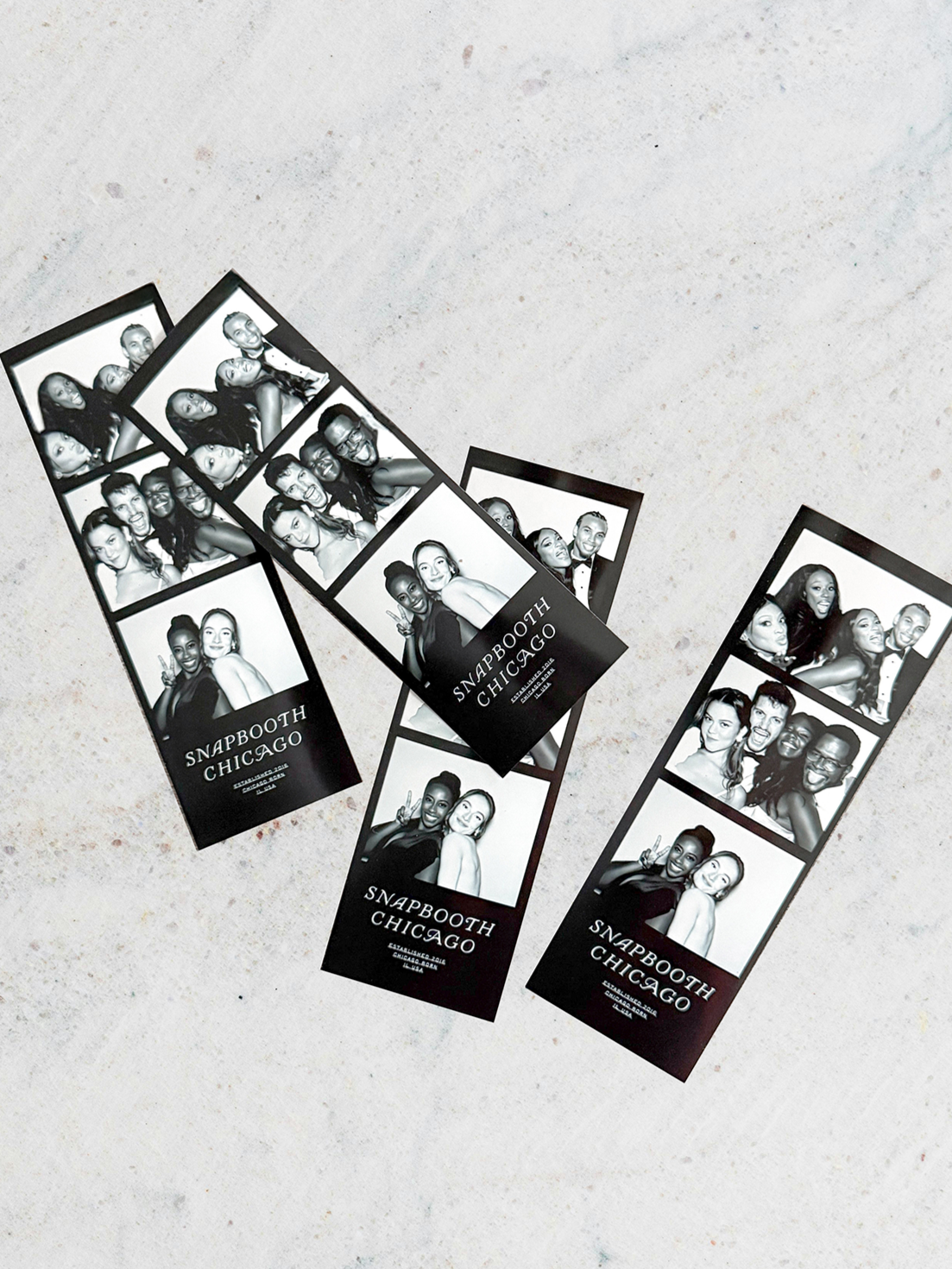 Black and white photo booth strips with groups of people smiling and showing peace signs, labeled 'SNAPBOOTH CHICAGO' with contact information.