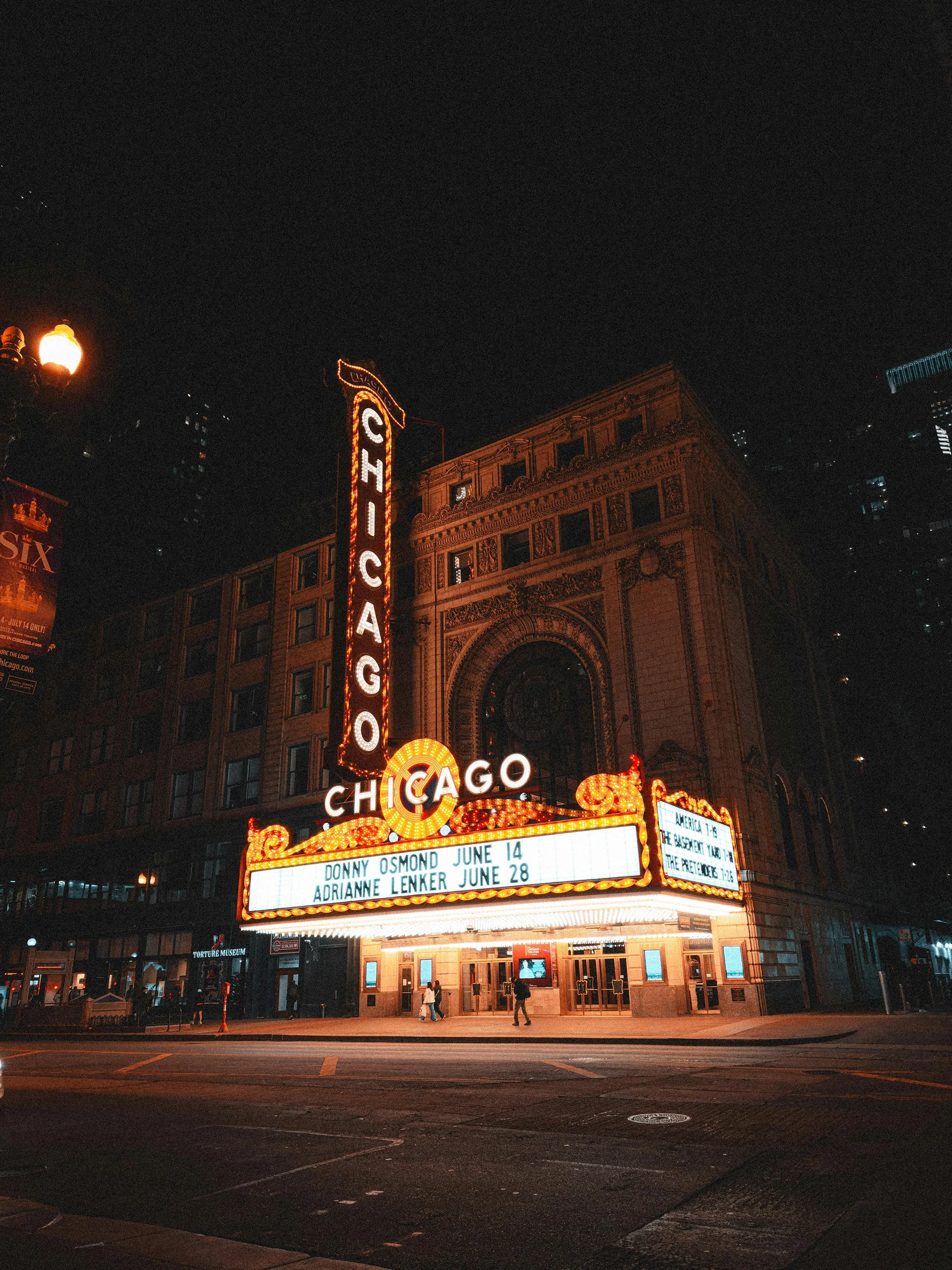 Chicago Theatre's illuminated marquee at night with show listings and a vertical sign reading 'Chicago'.