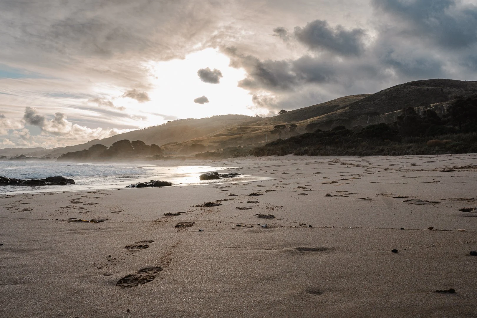 Sunset over beach with footprints in sand