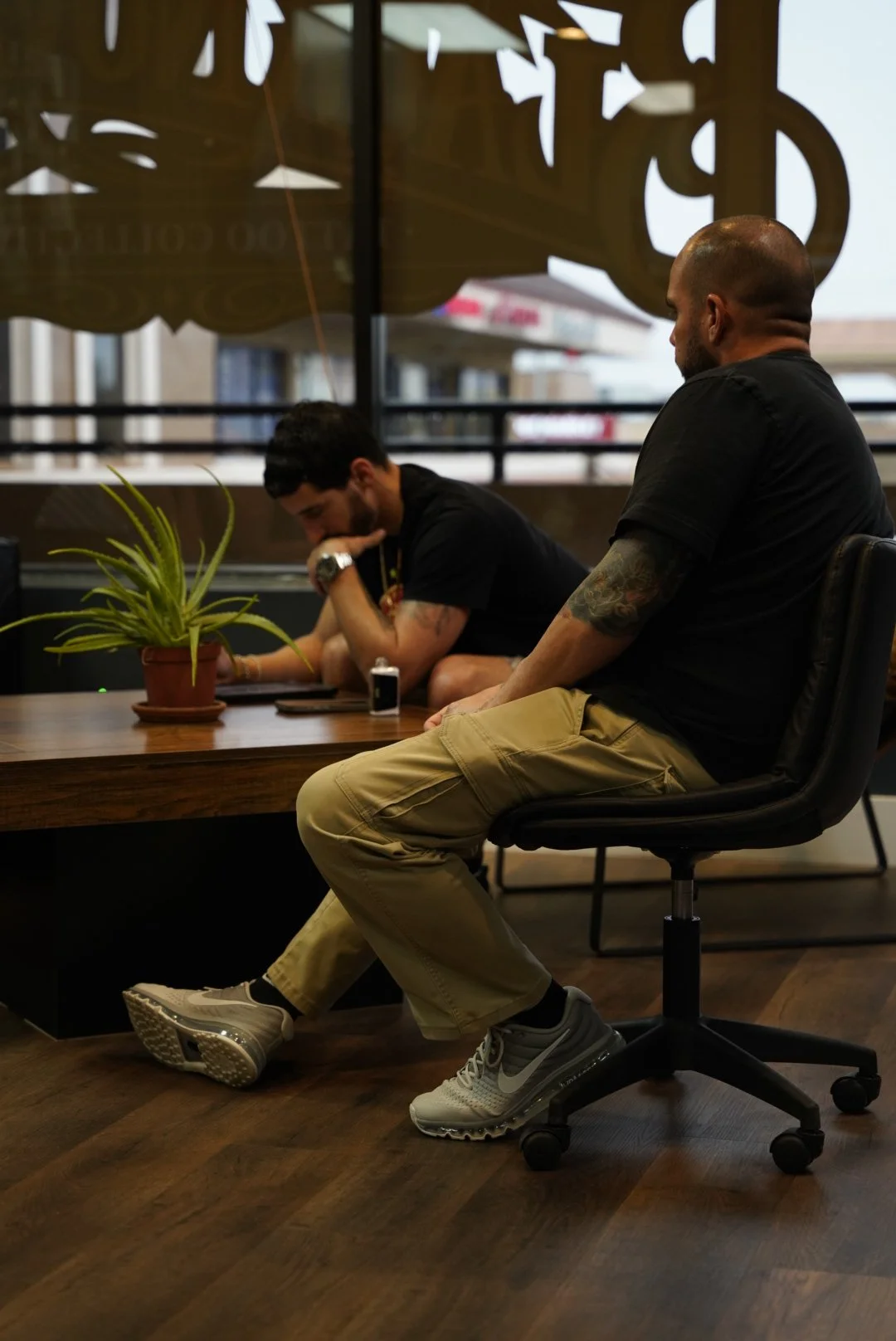 Tattoo consultation at Black Nova Tattoo Collective in Miami, showing an artist discussing a custom tattoo project with a client in the studio lounge.