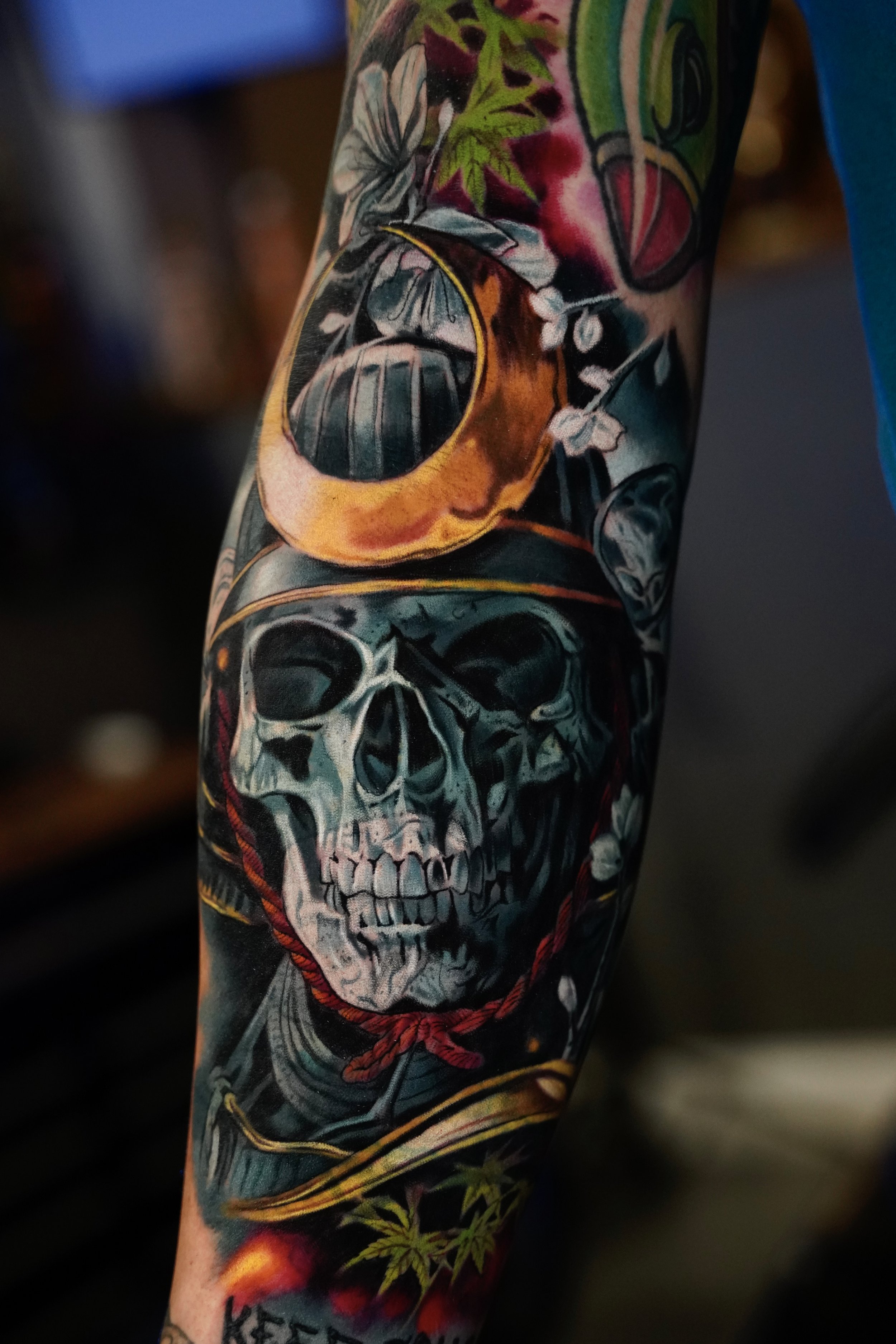 Dark realism cover-up featuring a skull composition with symbolic elements, deep contrast, and controlled color accents. Designed to integrate seamlessly into a large-scale sleeve flow.