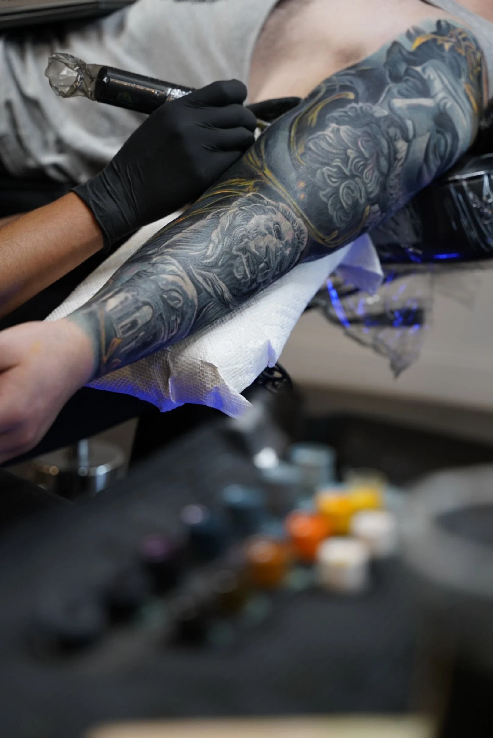 Tattoo artist working on large scale black and grey sleeve during custom cover up tattoo session
