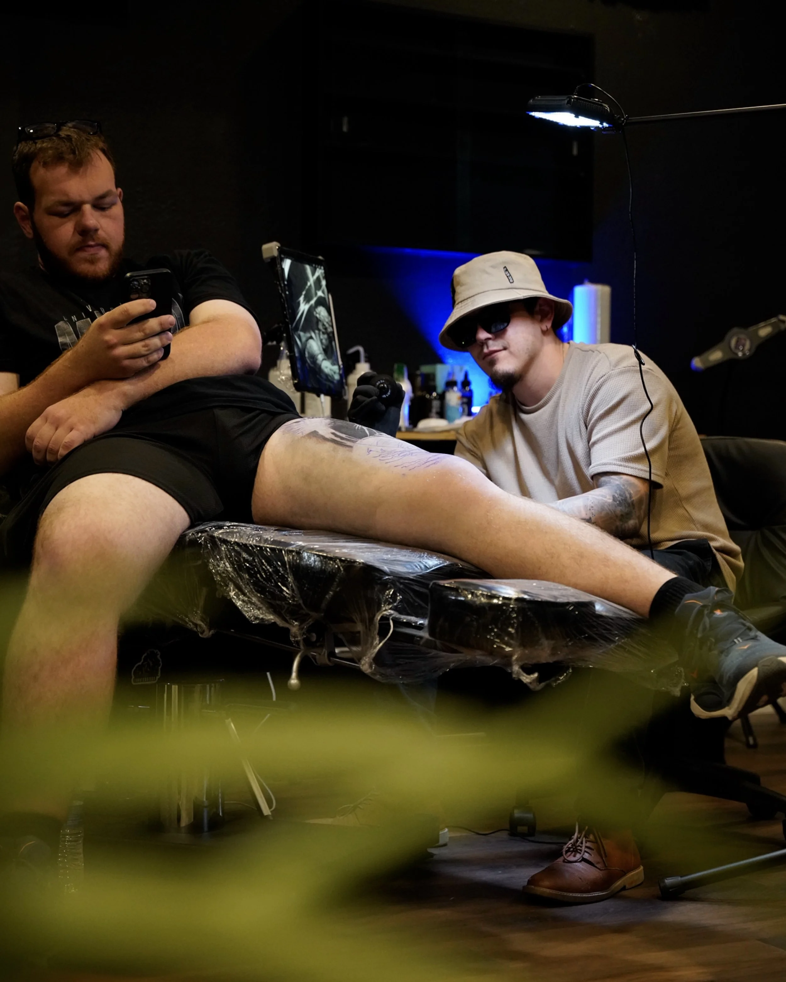 Tattoo artist working on a client’s leg at Black Nova Tattoo Collective in Miami.